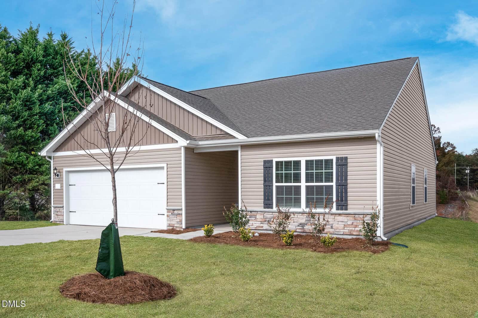Charming single-story beige house located at 104 Independence Lane in the heart of Oxford, featuring a white garage, stone accents, dark shutters, and a young tree in the front yard. The home sits on a well-kept lawn with neatly trimmed shrubs under a clear blue sky.