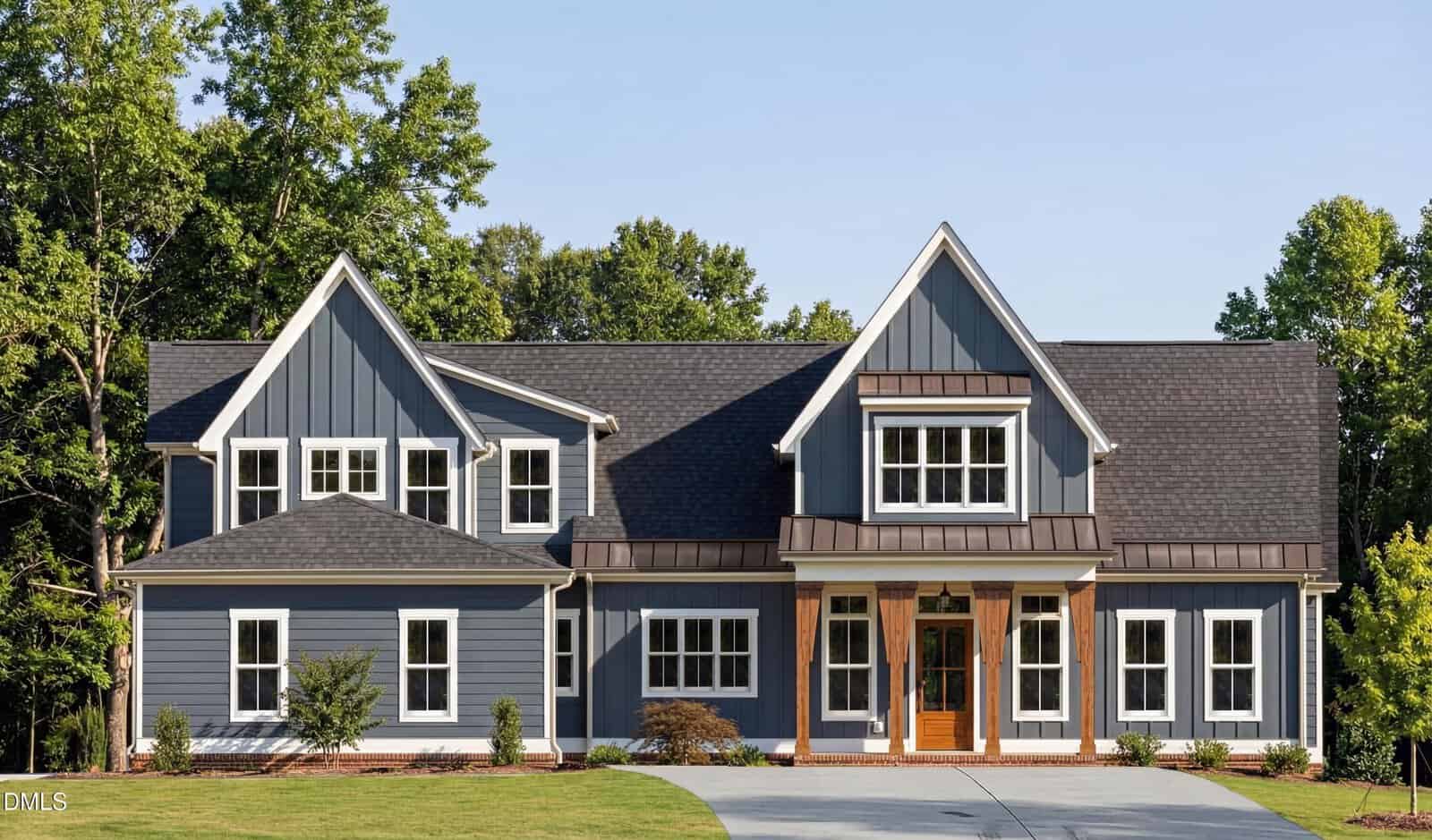 Charming two-story blue house with white trim located at 1411 Cottondale Lane in Wake Forest. Features a large front porch with wooden columns, multiple gables, and a driveway. Enjoy the green lawn in front and tall trees in the background.