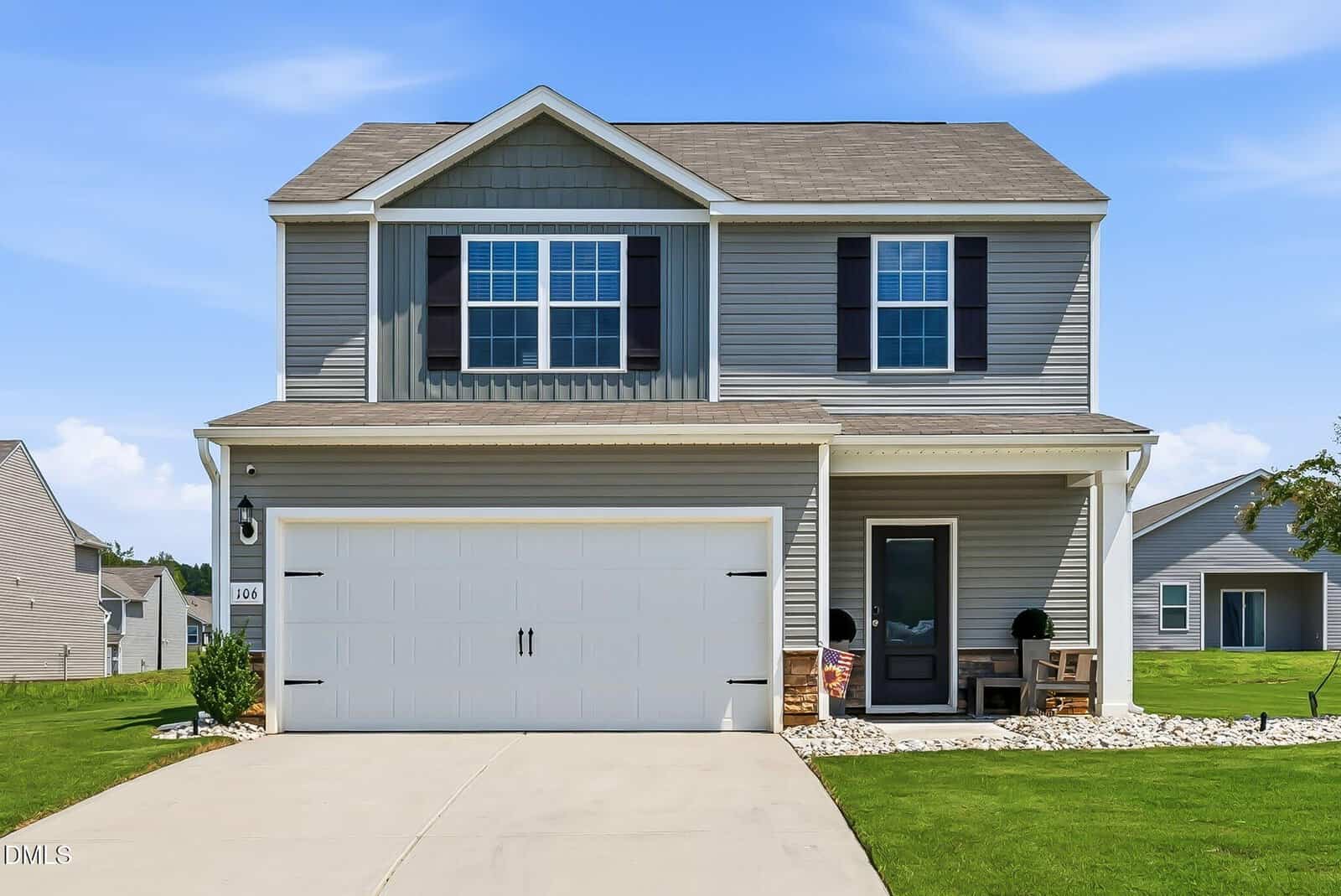 Charming two-story gray suburban house with white trim, located in Oxford at 106 Scoville Street; features a double garage, inviting front porch with seats, well-kept lawn, and a clear blue sky above.