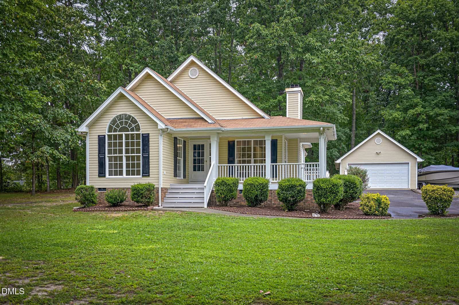 Beige single-story house with a front porch, gabled roof, large arched window, and detached garage at 4577 John Sandling Road in Franklinton, surrounded by green grass and trees.