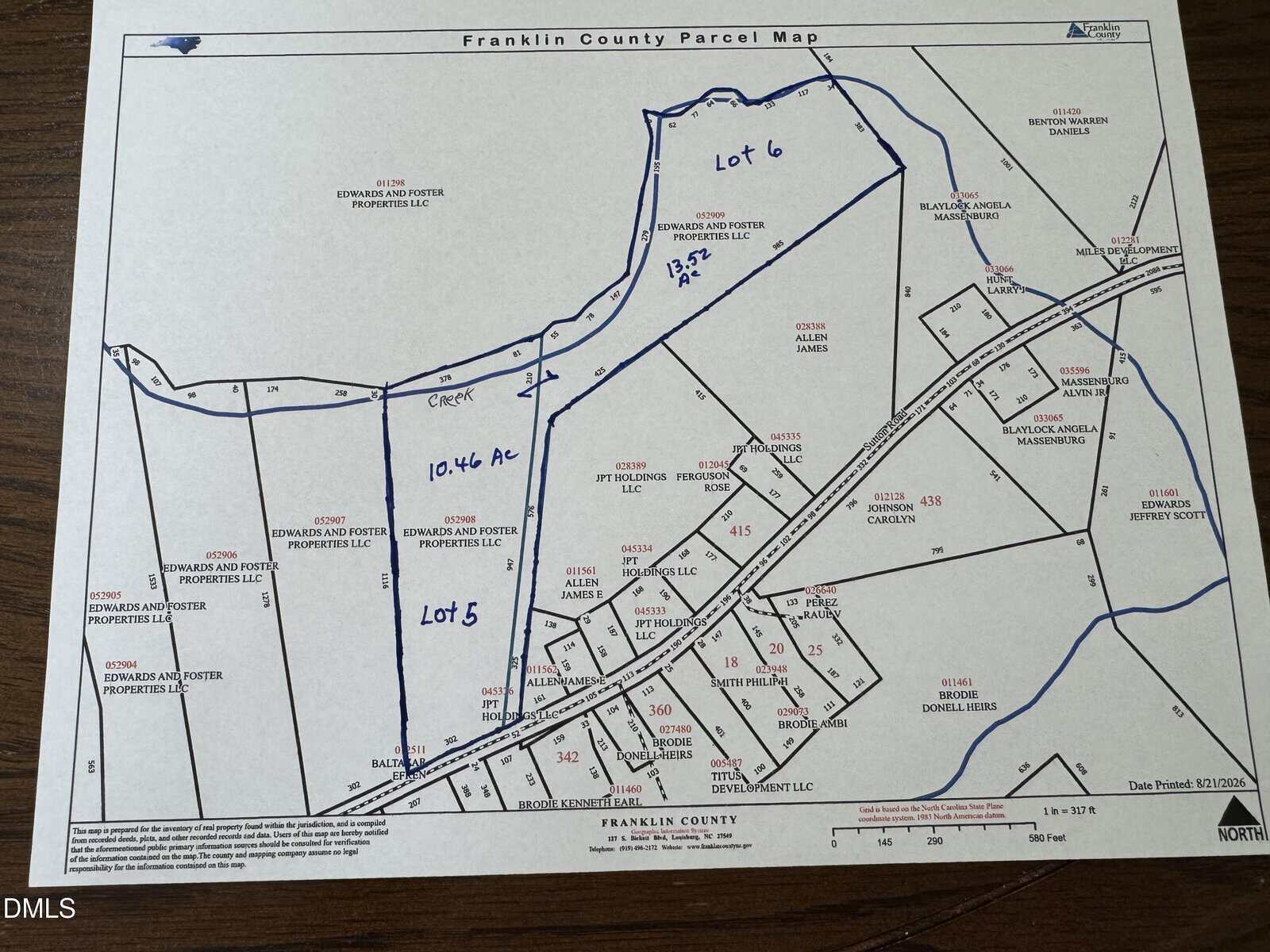 Franklin County parcel map showing outlined lots 5 (10.46 acres) and 6 on Sutton Rd near Louisburg, with parcels labeled by owner names, lot numbers, roads, and a creek drawn in blue ink. North arrow and map legend are included at the bottom.
