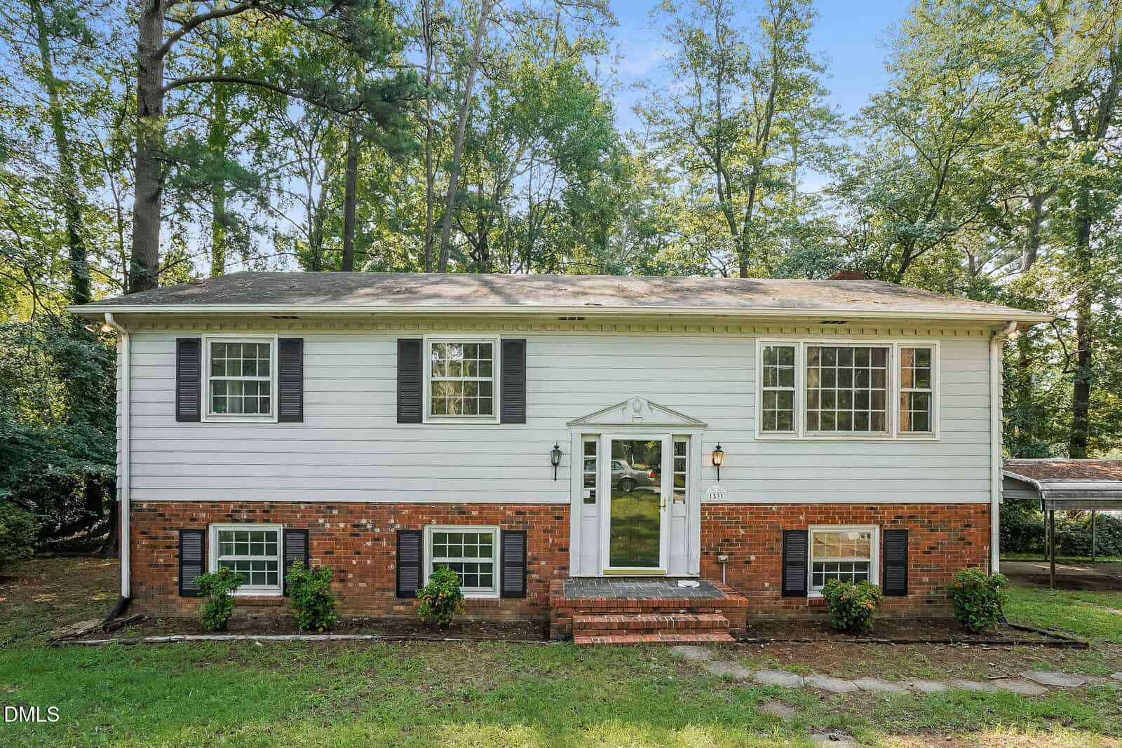 Charming two-story house at 1531 Hamlett Drive in Henderson, featuring white siding on the upper level, red brick on the lower level, black shutters, and large windows. A small porch with steps leads to the front door, surrounded by trees and greenery.