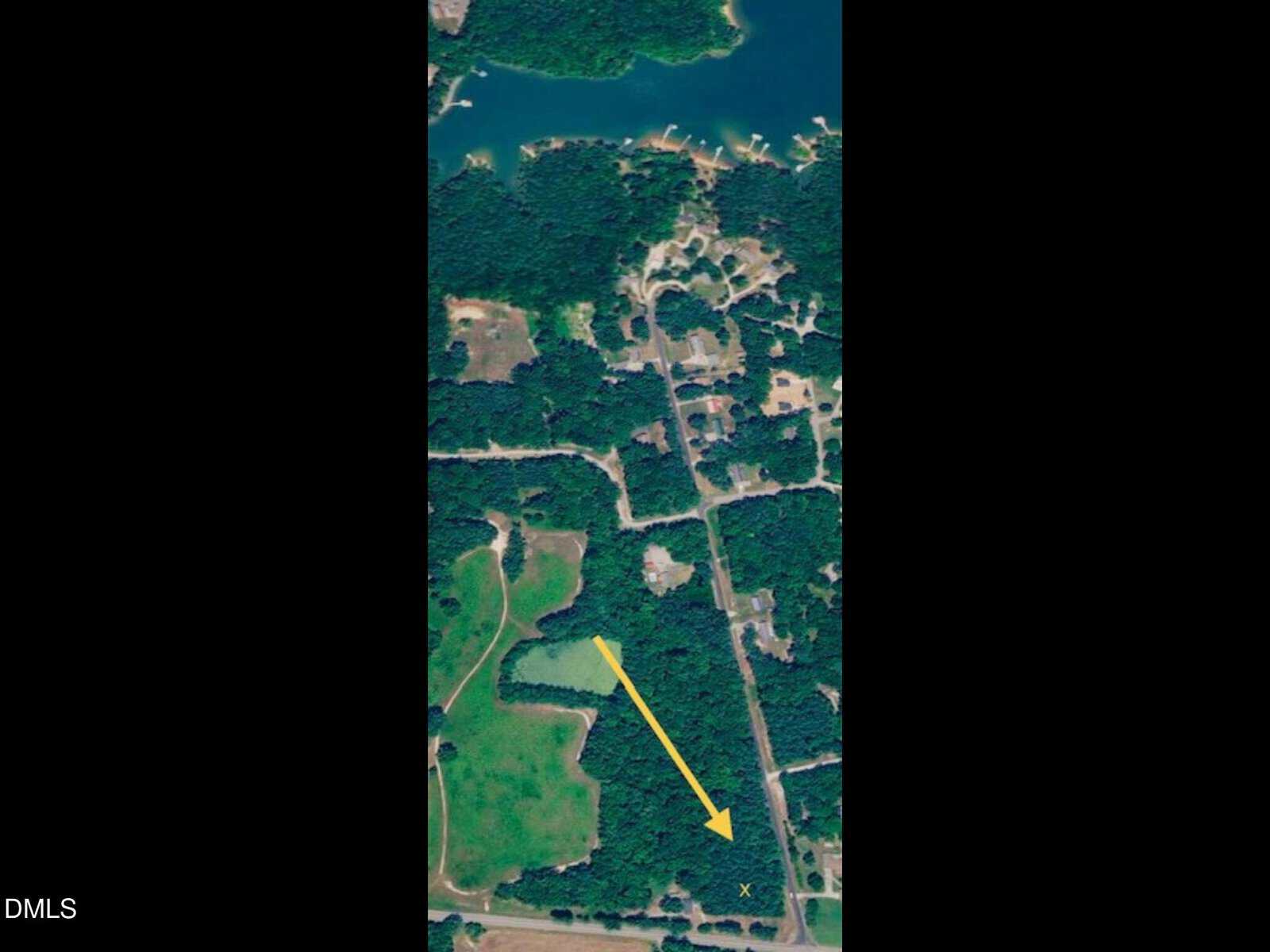A satellite view of a wooded and residential area near a lake, with a yellow arrow pointing from an open green field to a marked spot labeled “X” within the trees, just off 4647 Satterwhite Point Road in Henderson.