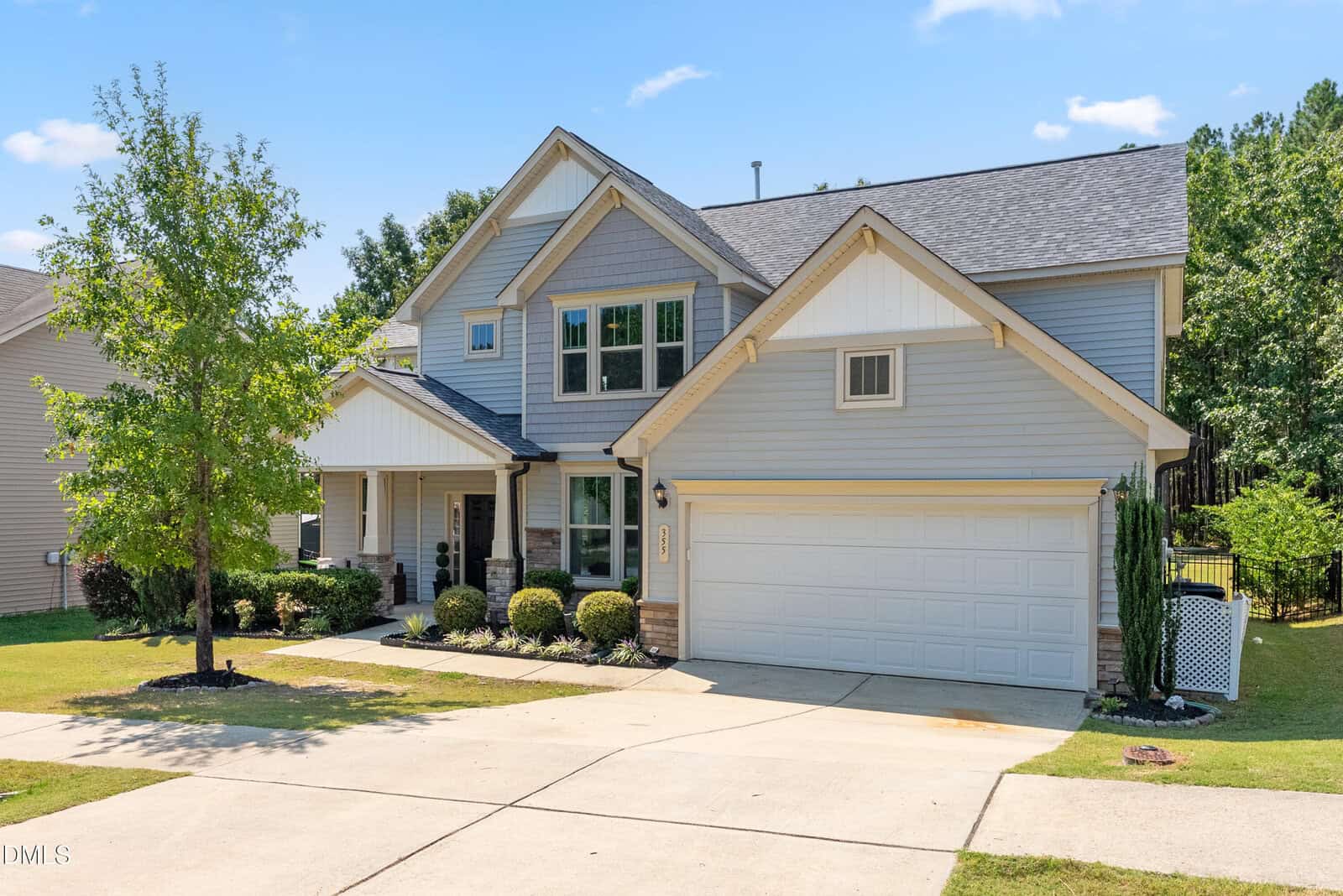 Two-story suburban house at 355 Clubhouse Drive, Youngsville, with gray siding, white trim, gable roof, double garage, front porch, landscaped yard, and a driveway. A small tree is near the driveway, with green grass and shrubs in the front yard.