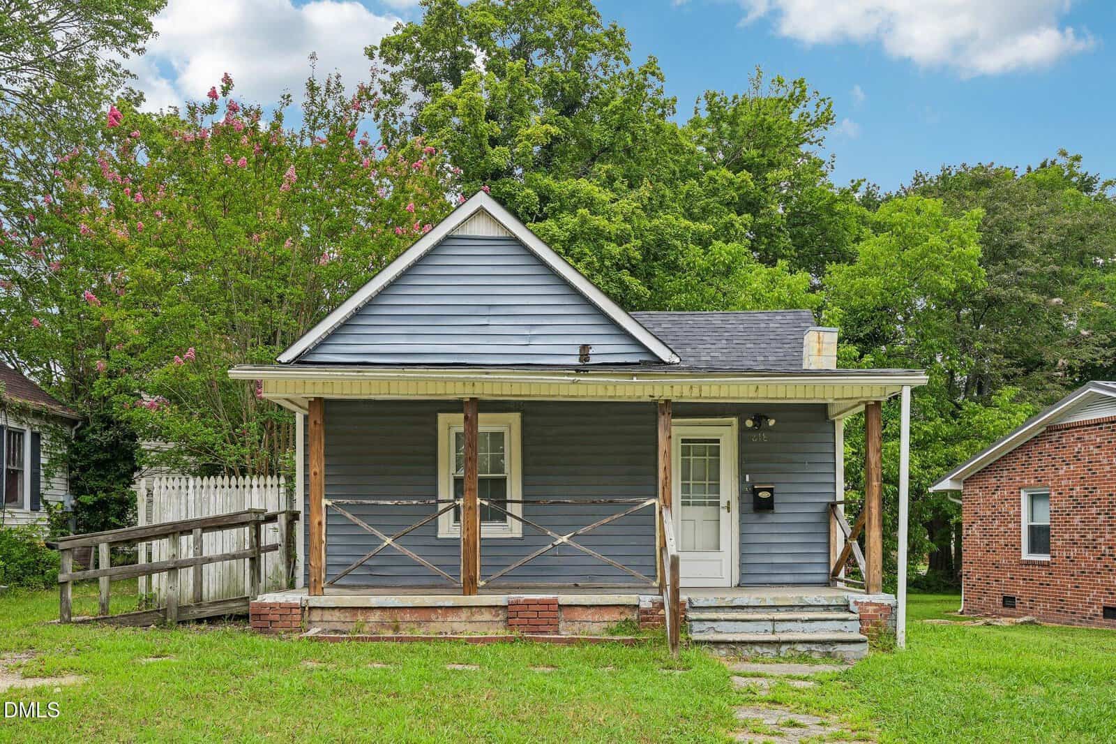 A small blue-gray house at 818 Dorsey Avenue, Henderson, with a front porch, wooden railings, white trim, and steps leading up to the door, surrounded by green trees and grass under a partly cloudy sky.
