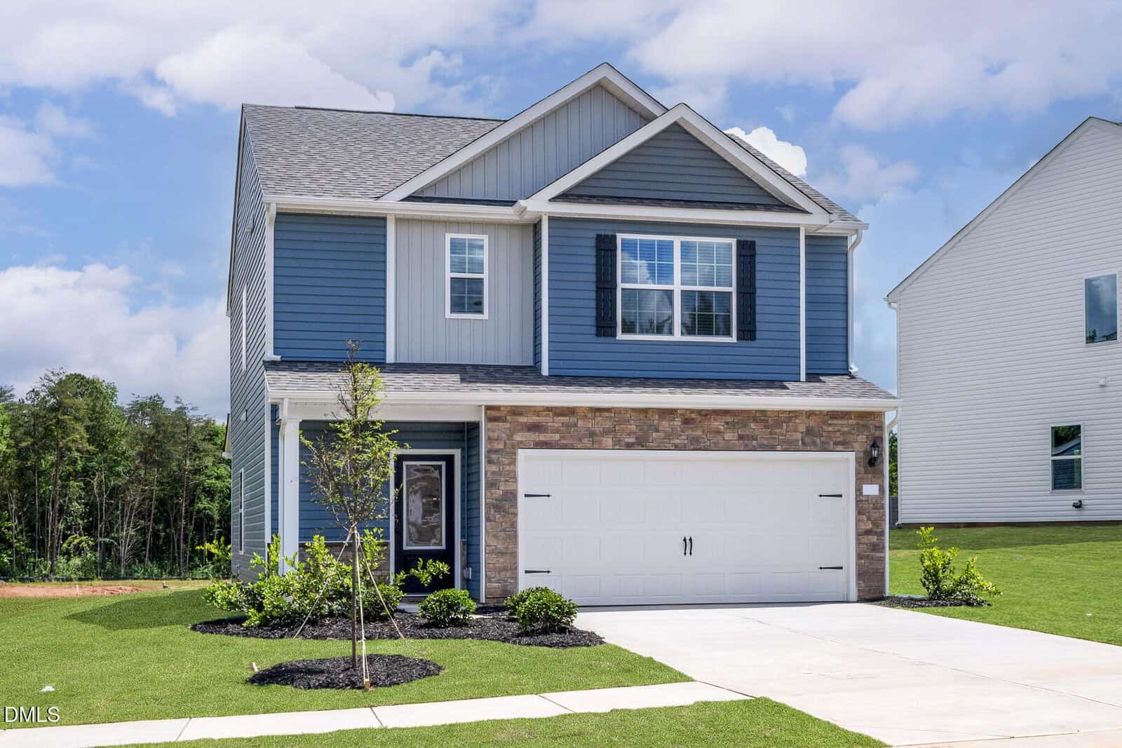 Two-story blue and gray house with white trim, brick accents, and a double garage is nestled at 1102 Rhino Bend, Oxford. Fresh landscaping surrounds the driveway, while the sky is partly cloudy and a neighboring white house is visible on the right.