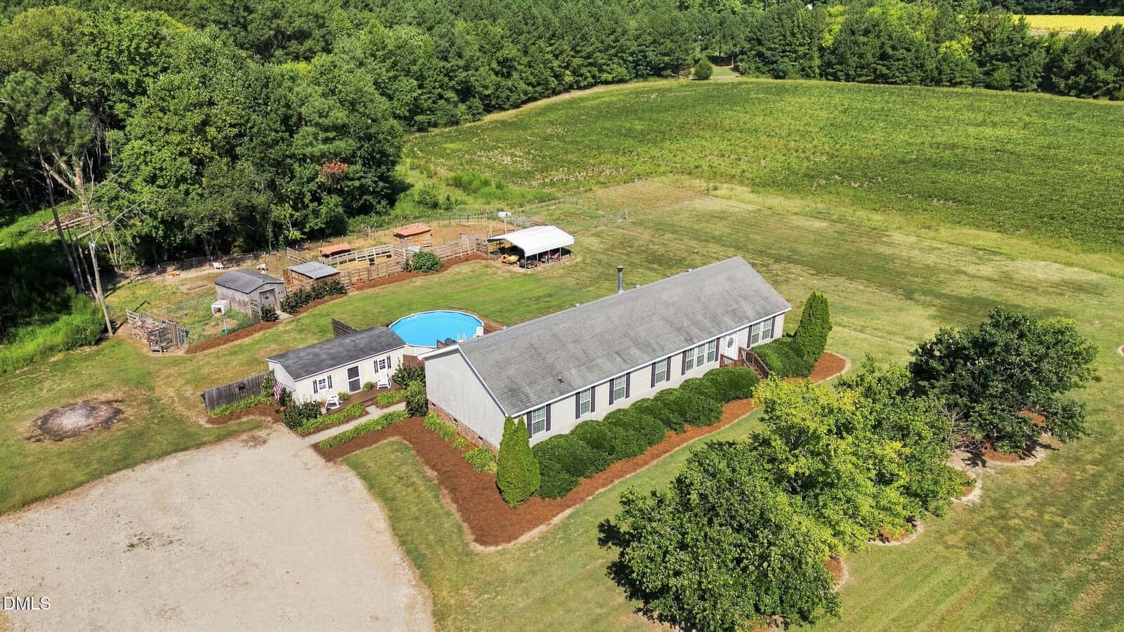 Aerial view of a single-story house with a pool, shed, and fenced yard at 4331 Nc 39 Highway N, Louisburg, surrounded by grass, trees, and open fields under a clear sky.