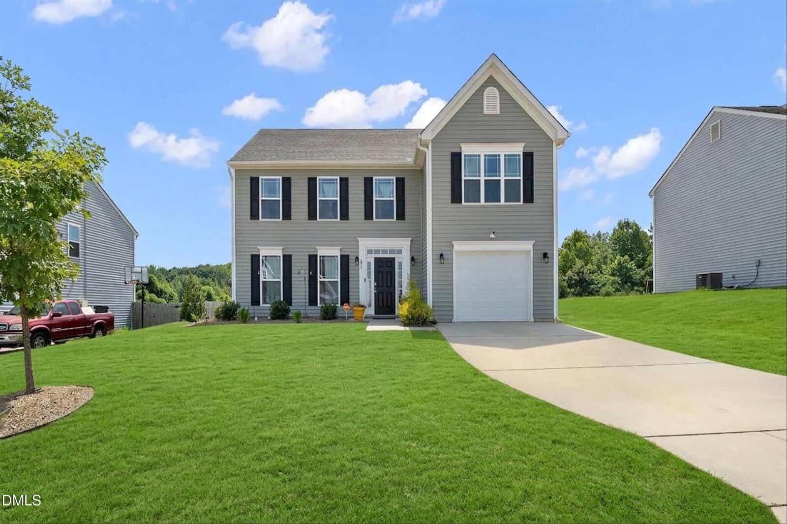 Two-story suburban house with gray siding, white trim, and a single-car garage located at 230 Rosewood Lane in Youngsville. Neatly mowed lawn, clear driveway, and potted plants near the front door complete the welcoming exterior. Blue sky with some clouds in the background.