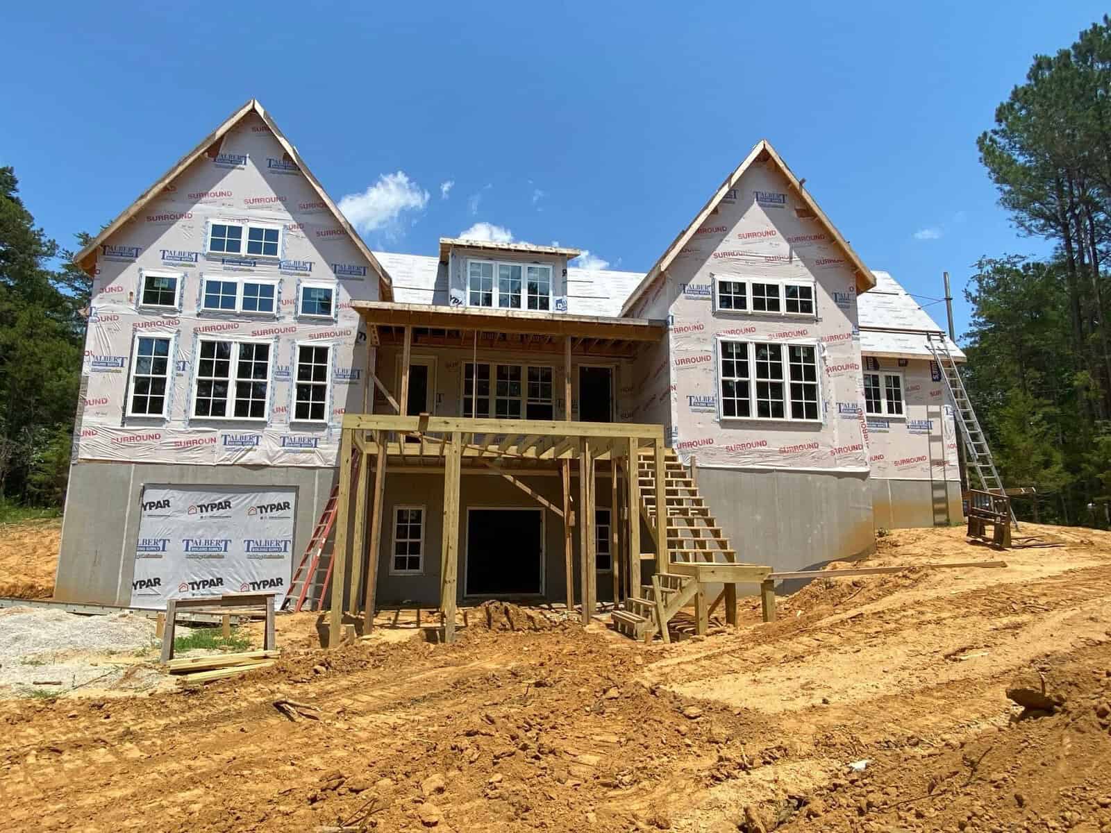 New residential home under construction at 764 Terry Lane, Henderson NC, with exposed wooden framing and house wrap on a dirt construction site with a ladder on the right side.