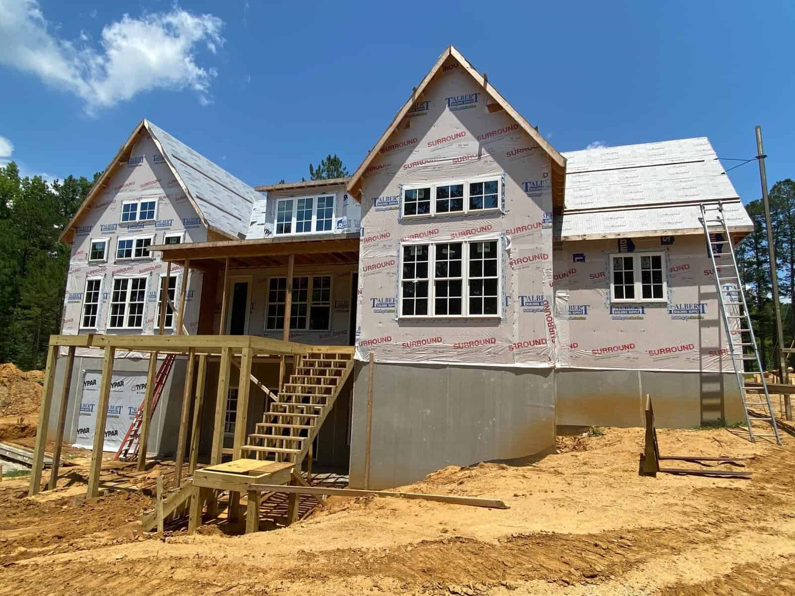 New residential house under construction, with partial siding installed and exposed weather-resistant barrier on the upper walls.