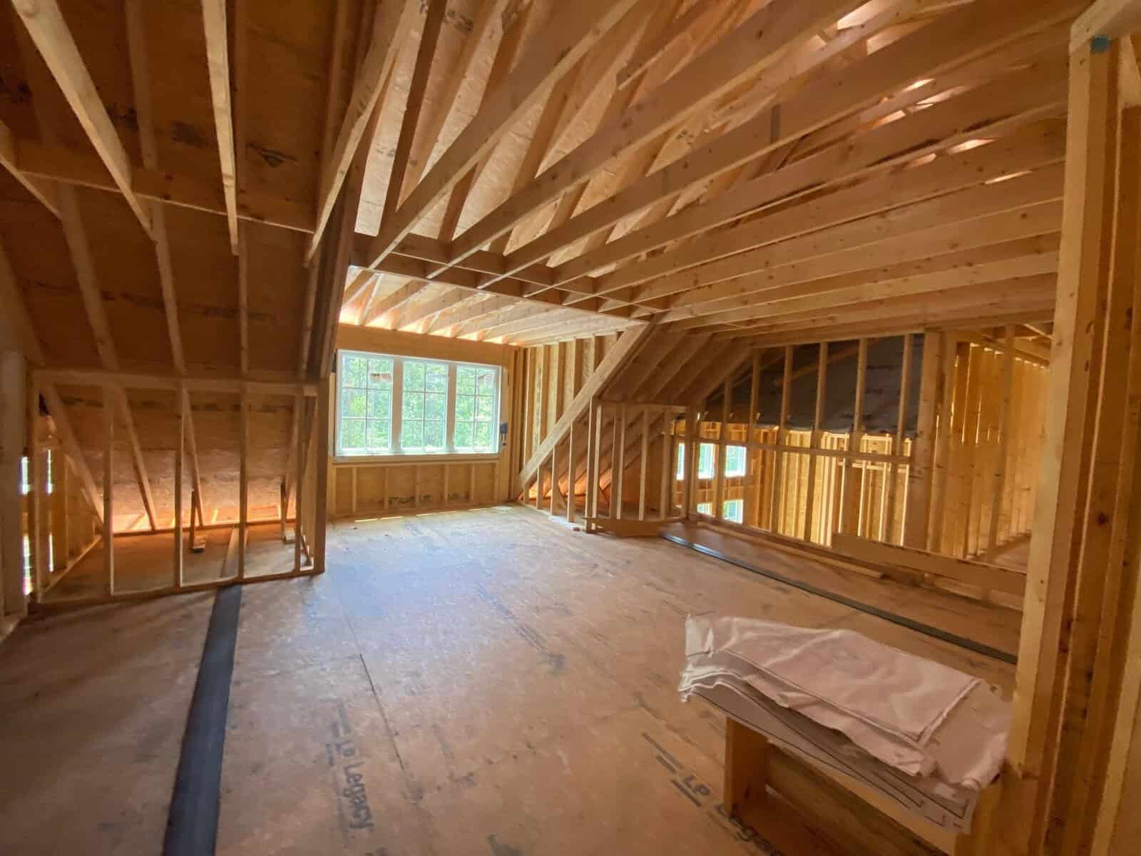 Interior of an unfinished attic space with exposed wooden framing and a window.