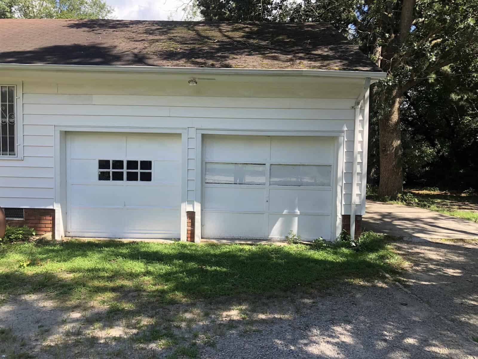 Two-car garage with white doors and windows on a sunny day.
