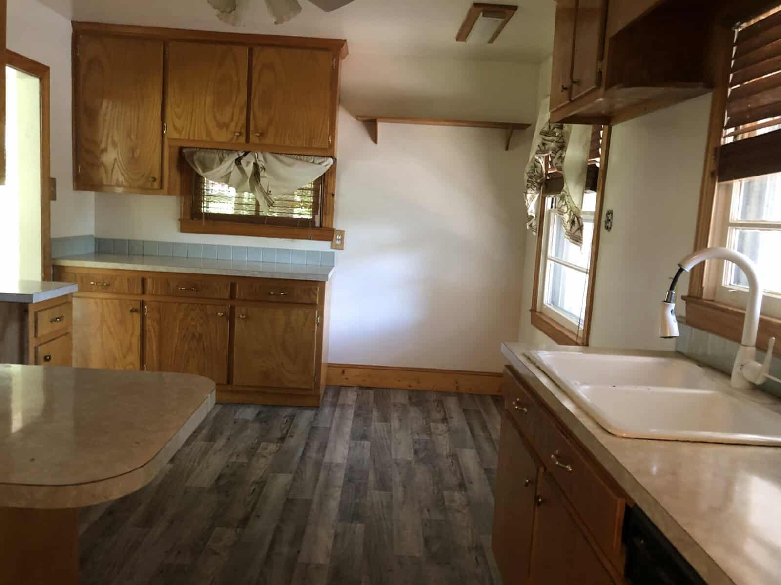 A spacious kitchen with wooden cabinets, laminate countertops, and vinyl flooring displaying a traditional design.