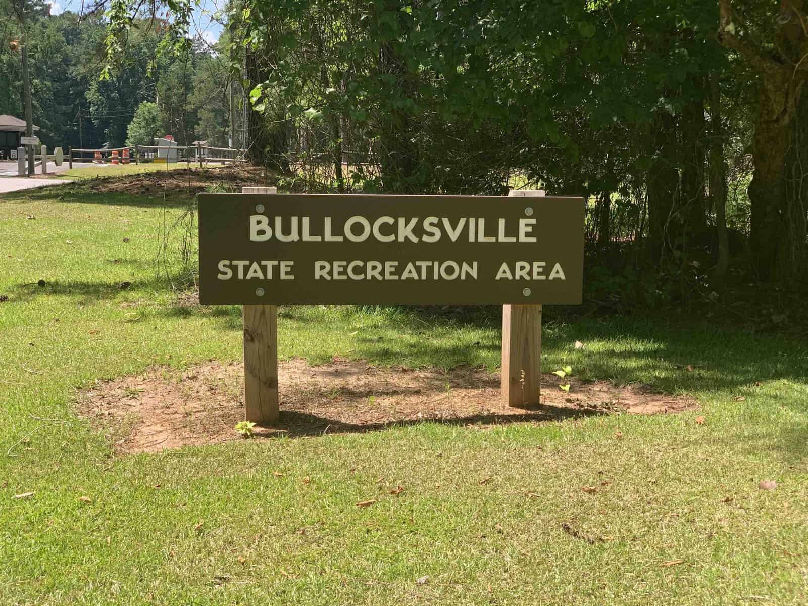 A sign reads "Bullocksville State Recreation Area" set on a grassy area with trees in the background.