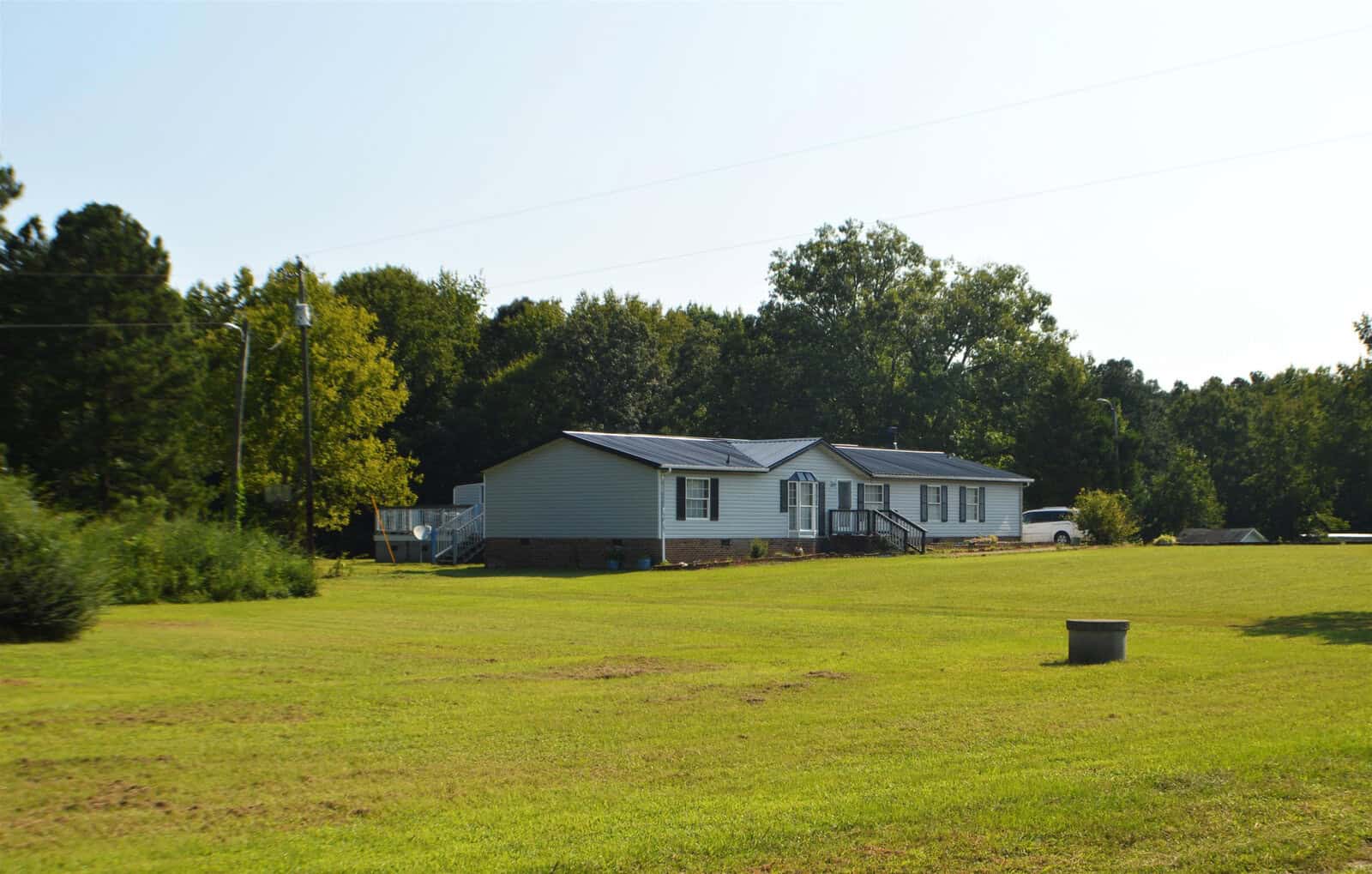 A single-story house with a gray exterior sits on a large, freshly-mowed lawn at 63 New Circle Lane, Henderson NC, under a clear sky.