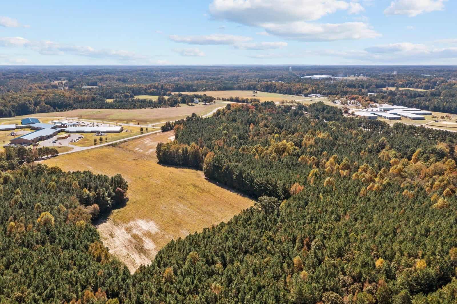 Aerial view of a rural landscape along 0 Garrett Road, Henderson, NC showing a patchwork of forested areas, open fields, and several buildings.