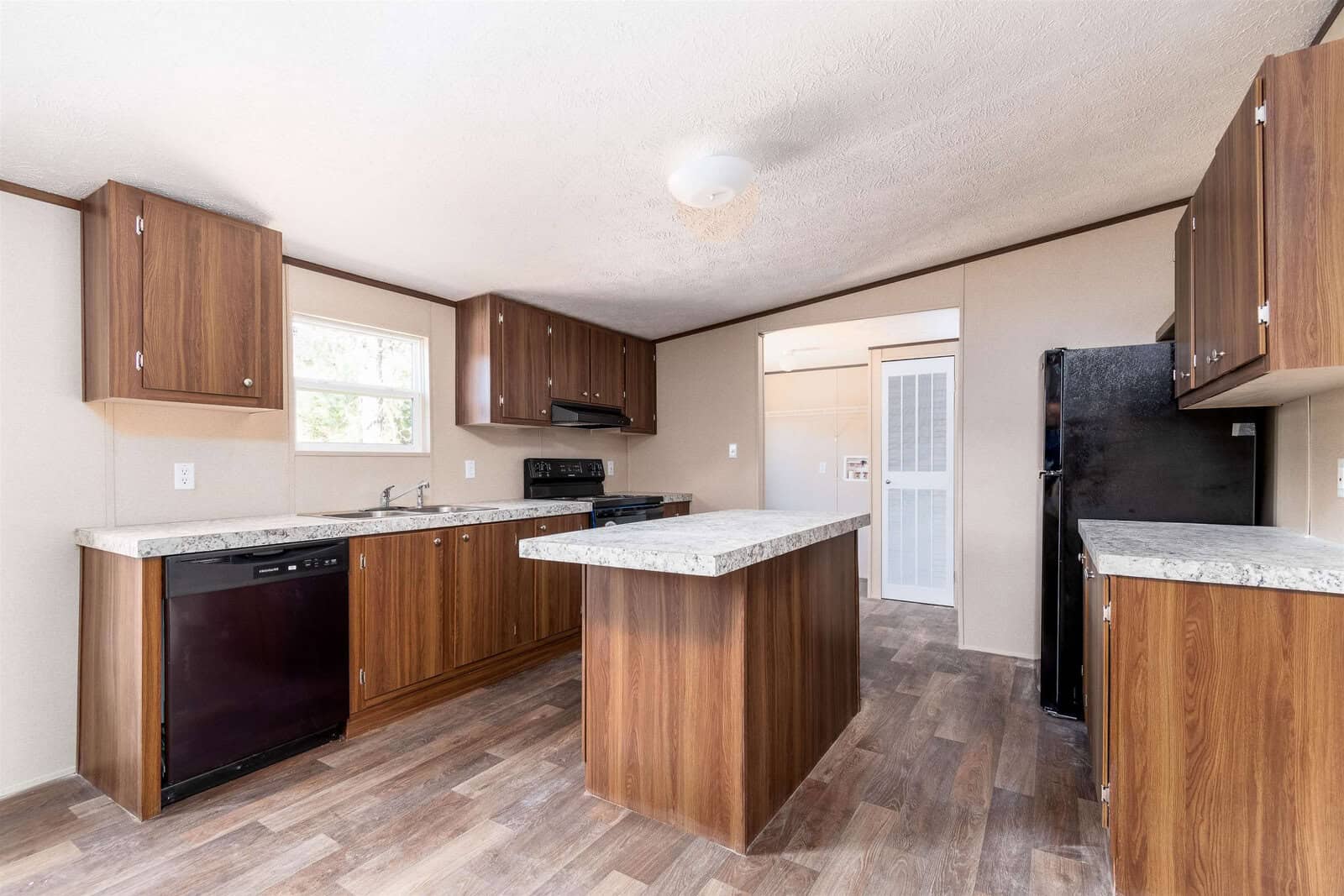 A newly renovated kitchen with wooden cabinets, granite countertops, modern appliances, and laminate flooring.
