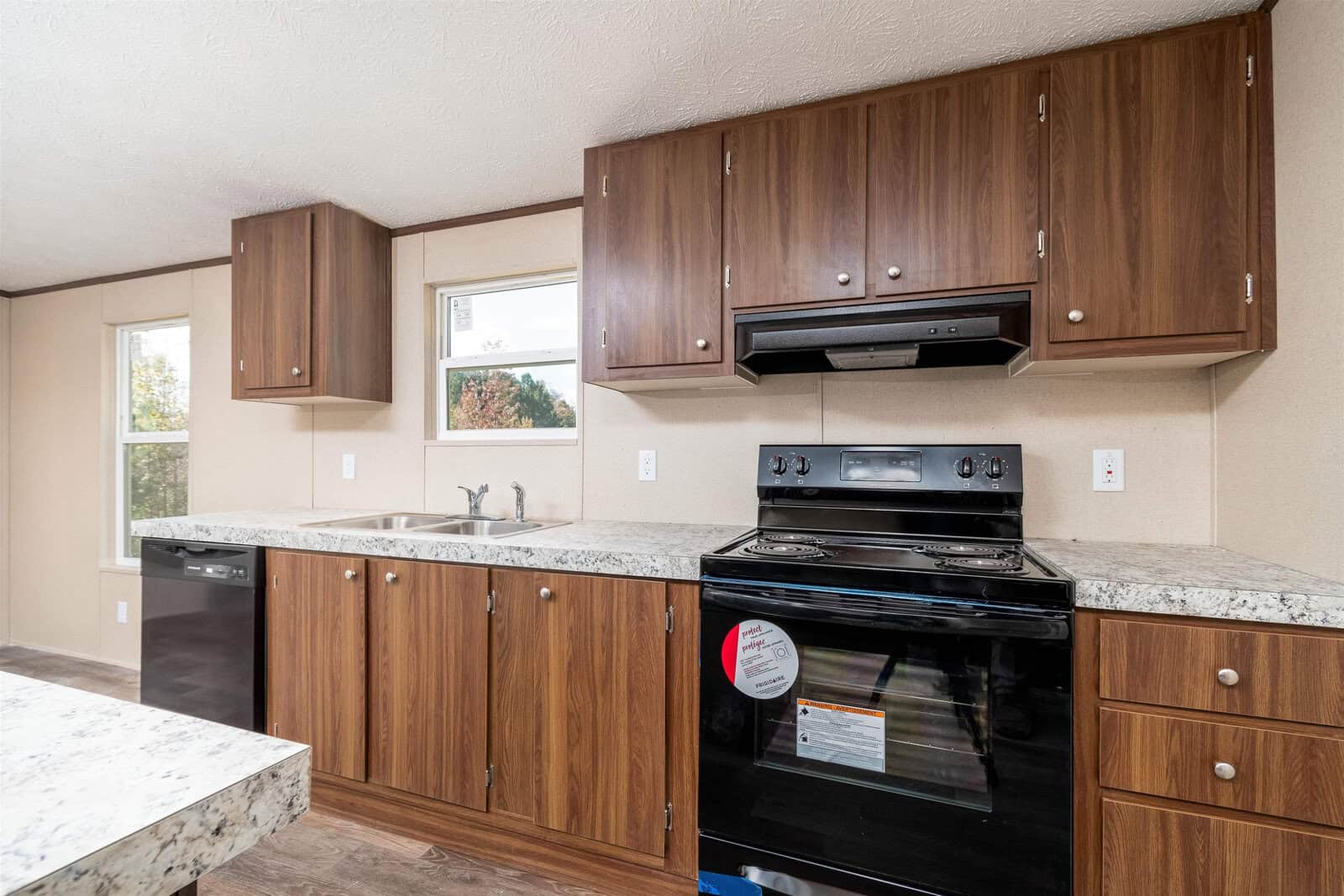 A modern kitchen interior with wooden cabinets, granite countertops, and stainless steel appliances.