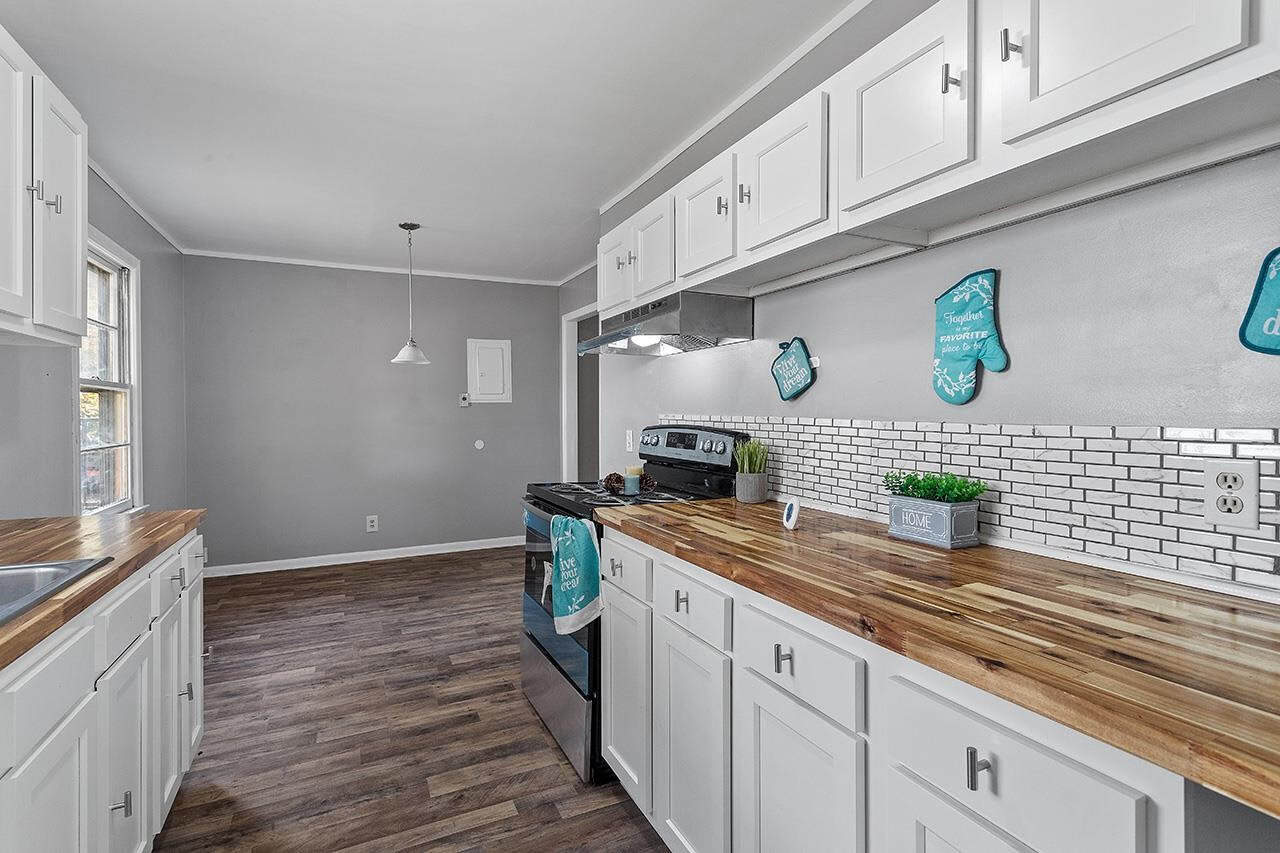 A modern kitchen with white cabinetry, stainless steel appliances, a subway tile backsplash, and wooden countertops.