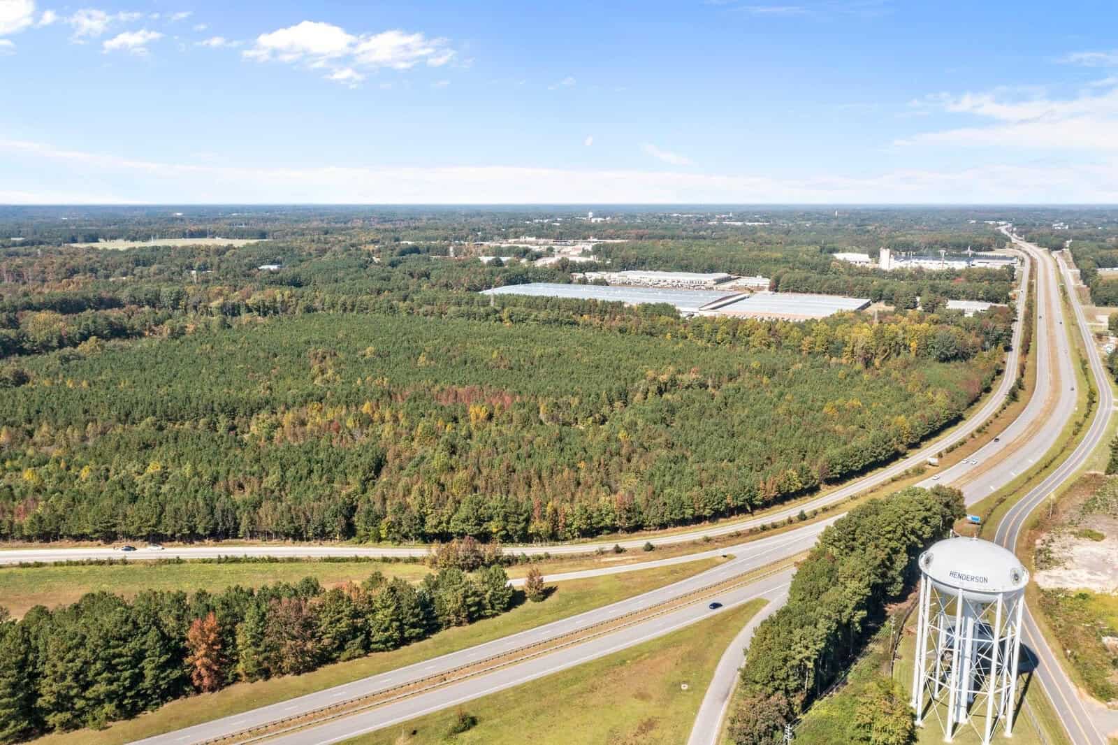 An aerial view of Facet Road interchange with a water tower in the foreground and a mix of industrial buildings and wooded areas in the background.