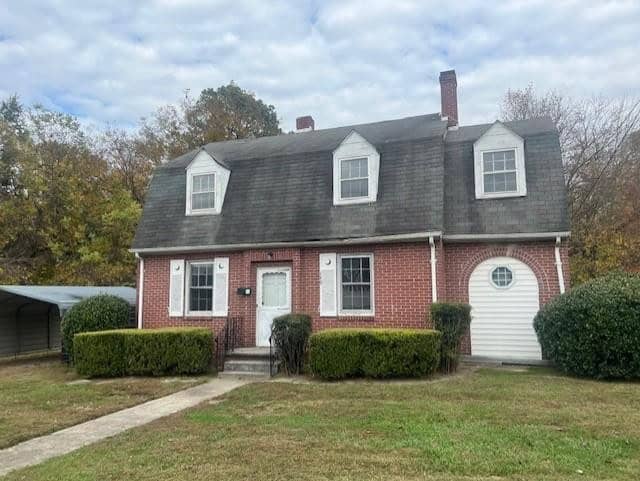 A two-story red brick house at 140 W Andrews Avenue, Henderson NC, with a dark shingled roof, white trim around the doors and windows, a central white front door, and a