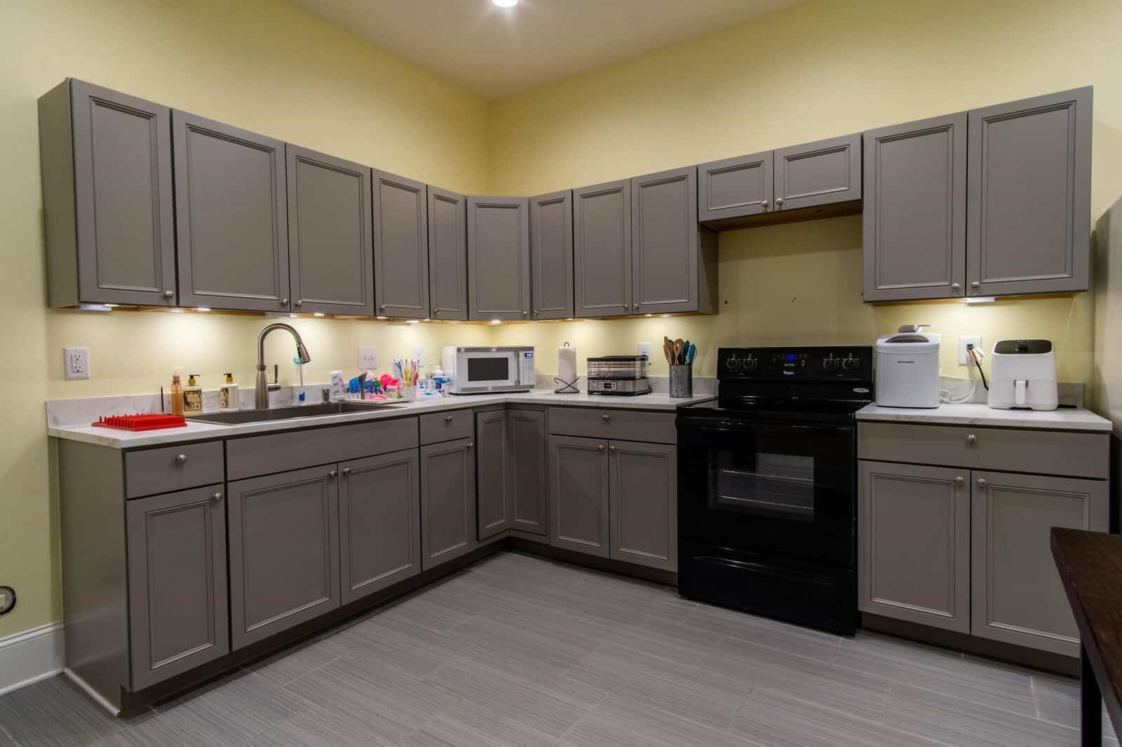 A modern kitchen with gray cabinetry, stainless steel appliances, and laminate flooring.