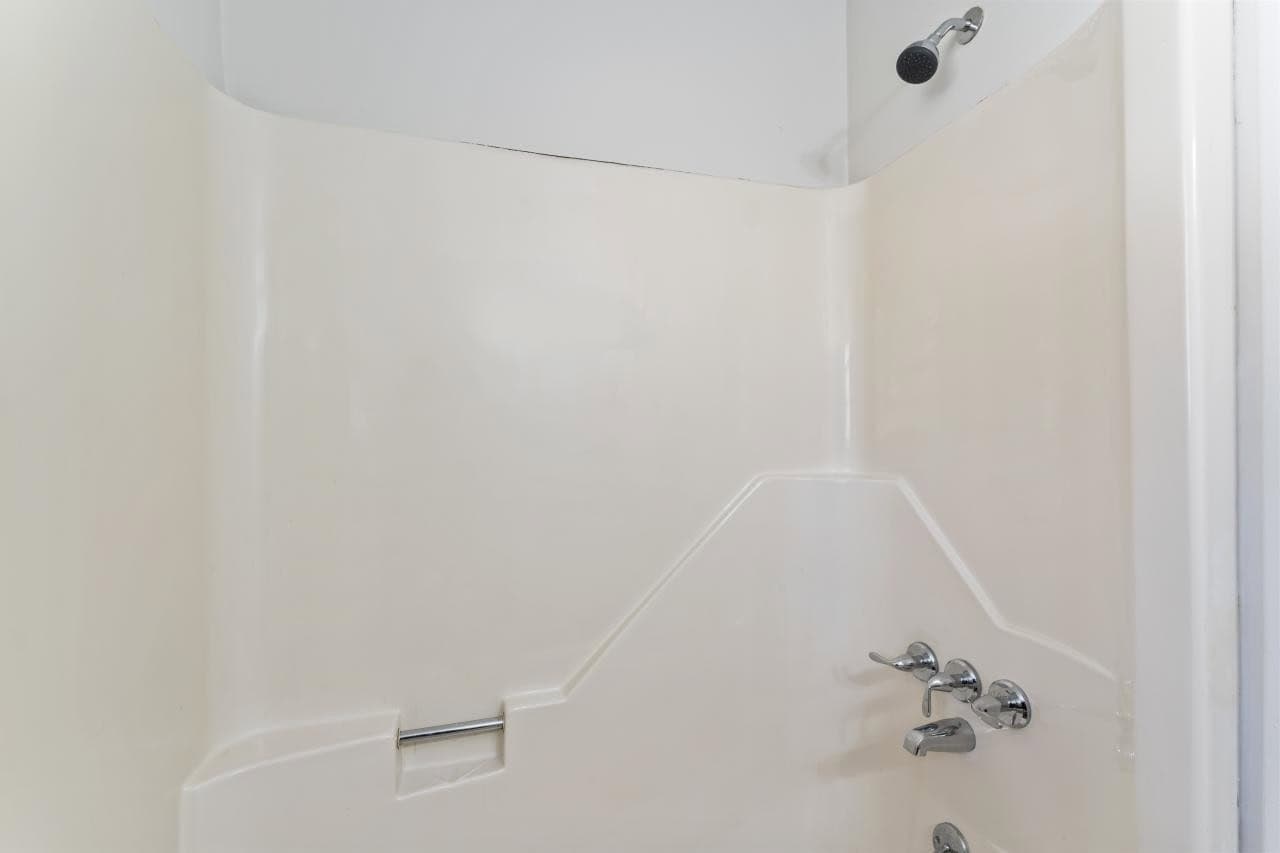 A white bathtub with mounted fixtures and a safety grab bar on the wall.