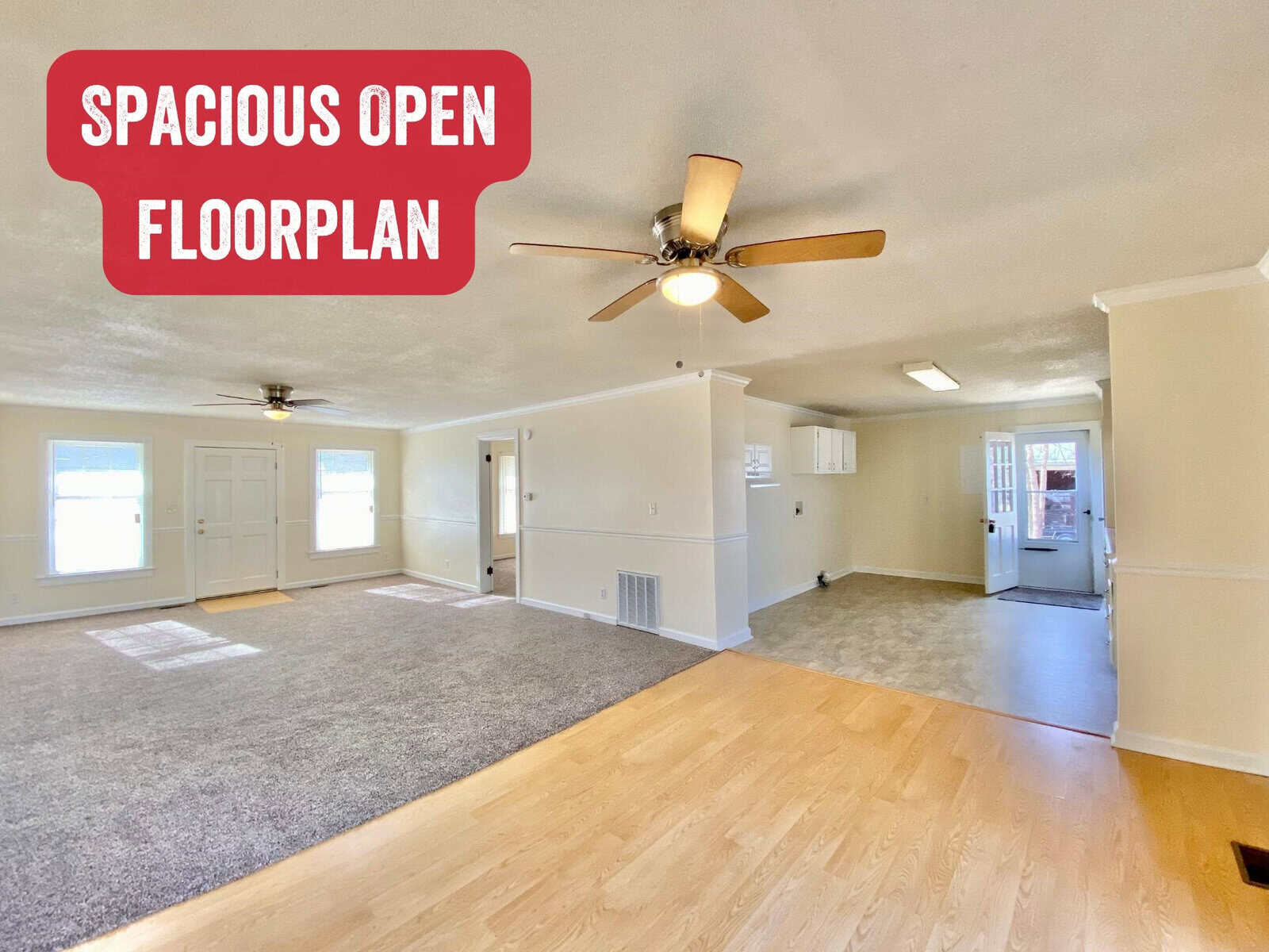 An empty interior showing a spacious open floor plan with mixed flooring, natural light, and ceiling fans.