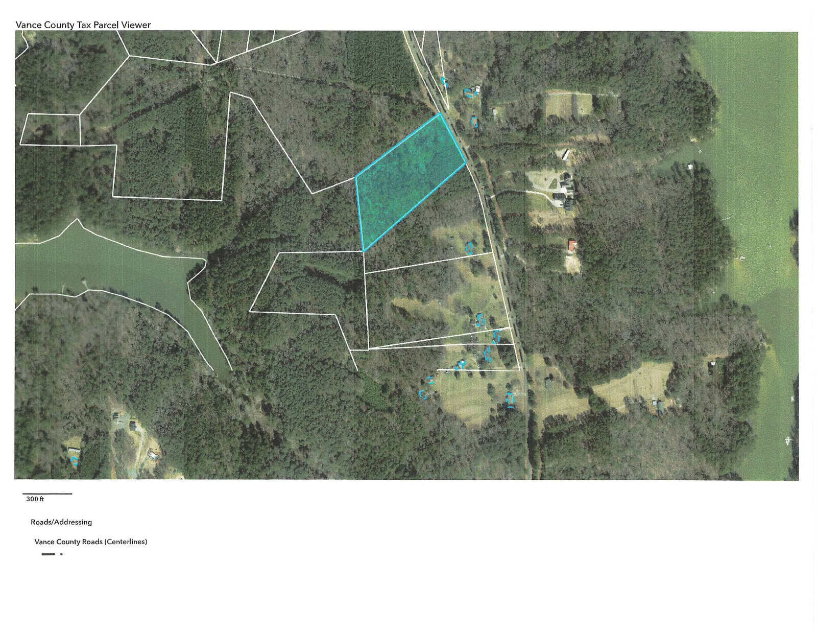 Aerial map view shows a wooded area with a highlighted parcel of land bordered in blue, located near Lot 6 County Line Park Road. Surrounding the parcel are other plots and roads, with scattered houses amidst the trees, just outside of Manson.