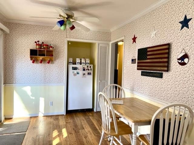 A cozy dining room with a wooden table, white chairs, a refrigerator adorned with magnets, and walls decorated with patriotic-themed items, including stars and an american flag.