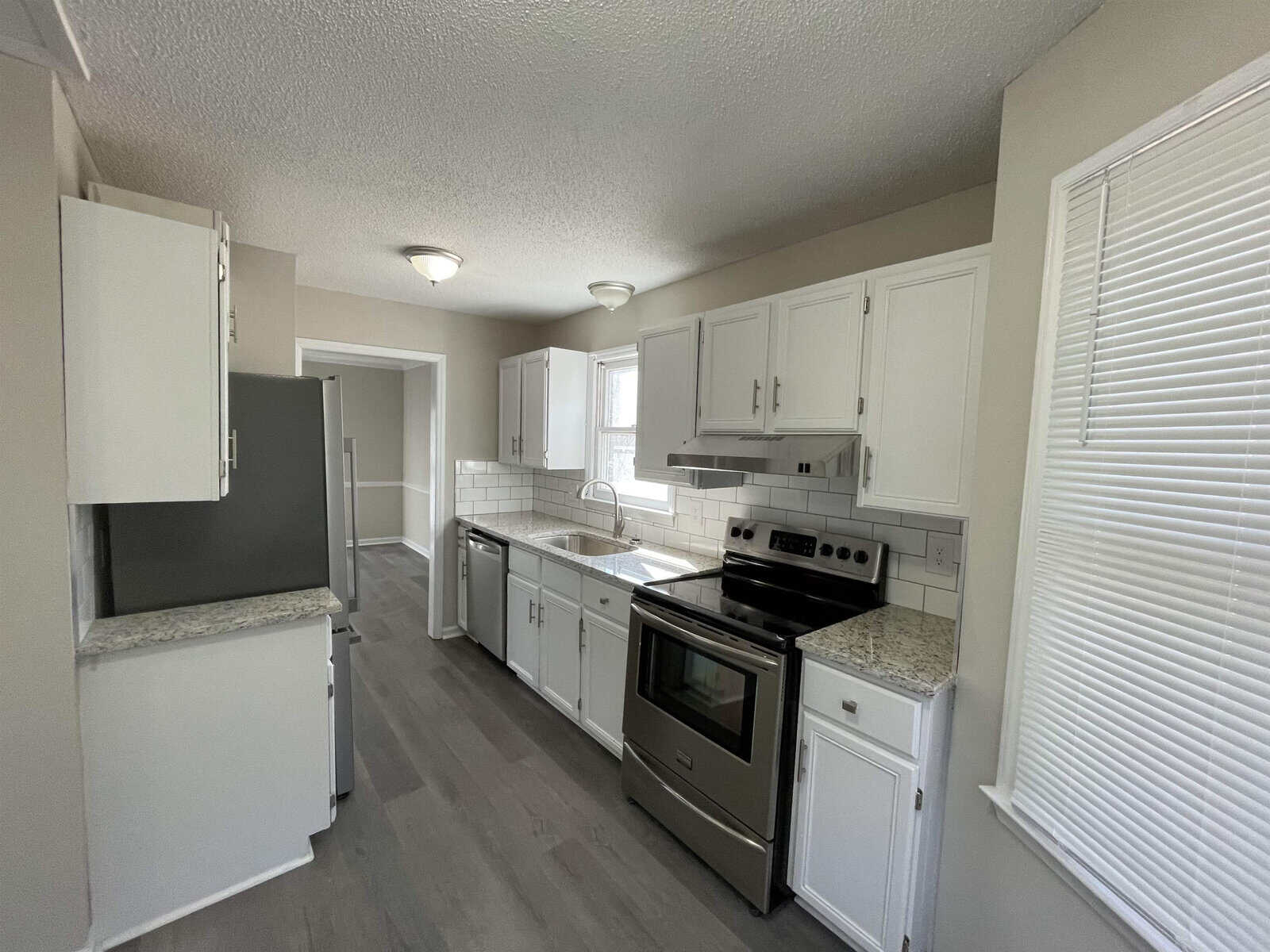 A tidy kitchen interior with white cabinetry, modern appliances, and grey flooring.