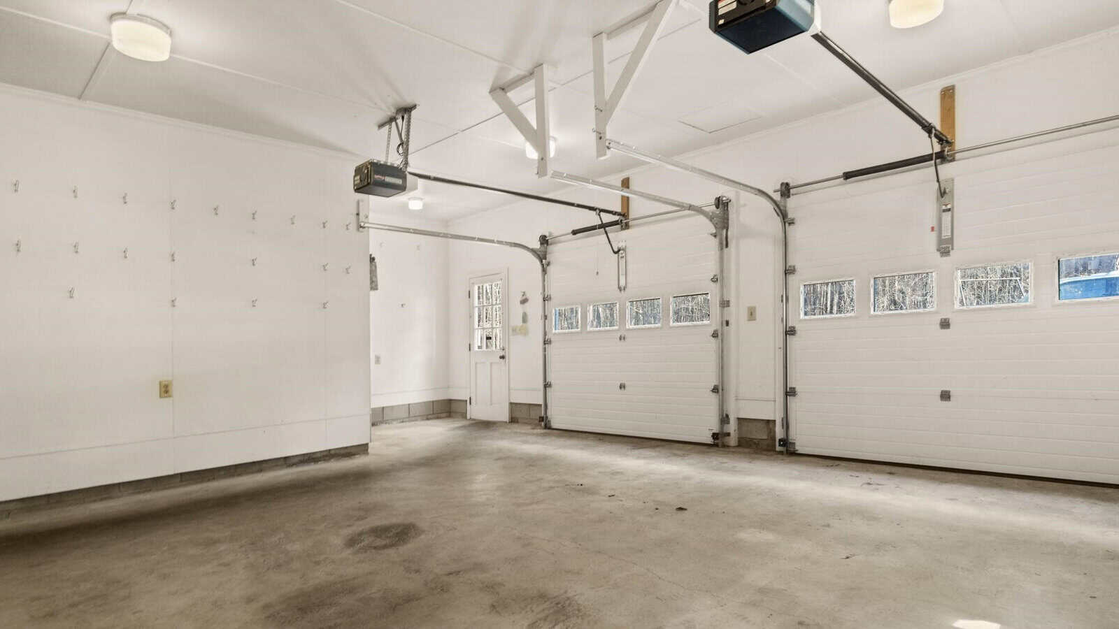 Empty two-car garage with white walls, two closed doors, and an automatic door opener system.