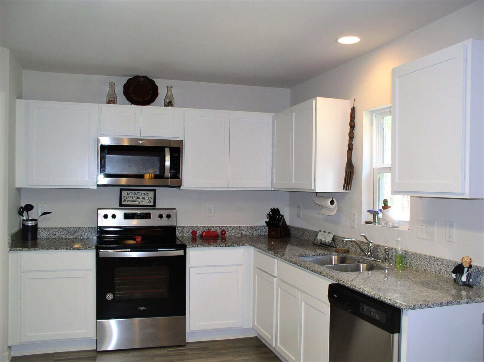 A modern kitchen with white cabinetry, stainless steel appliances, and granite countertops.