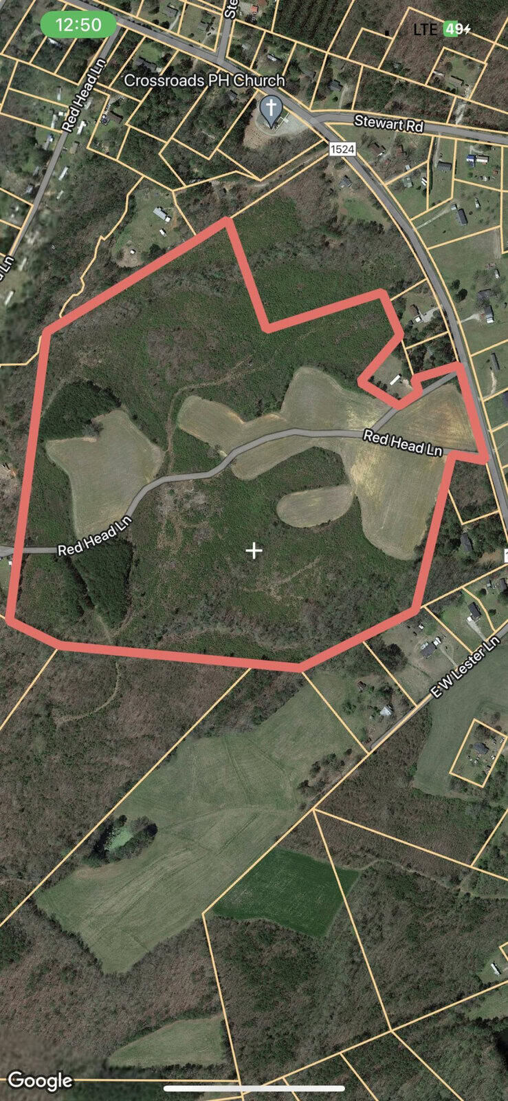 Aerial view of a rural area with a highlighted property boundary on a smartphone map application.