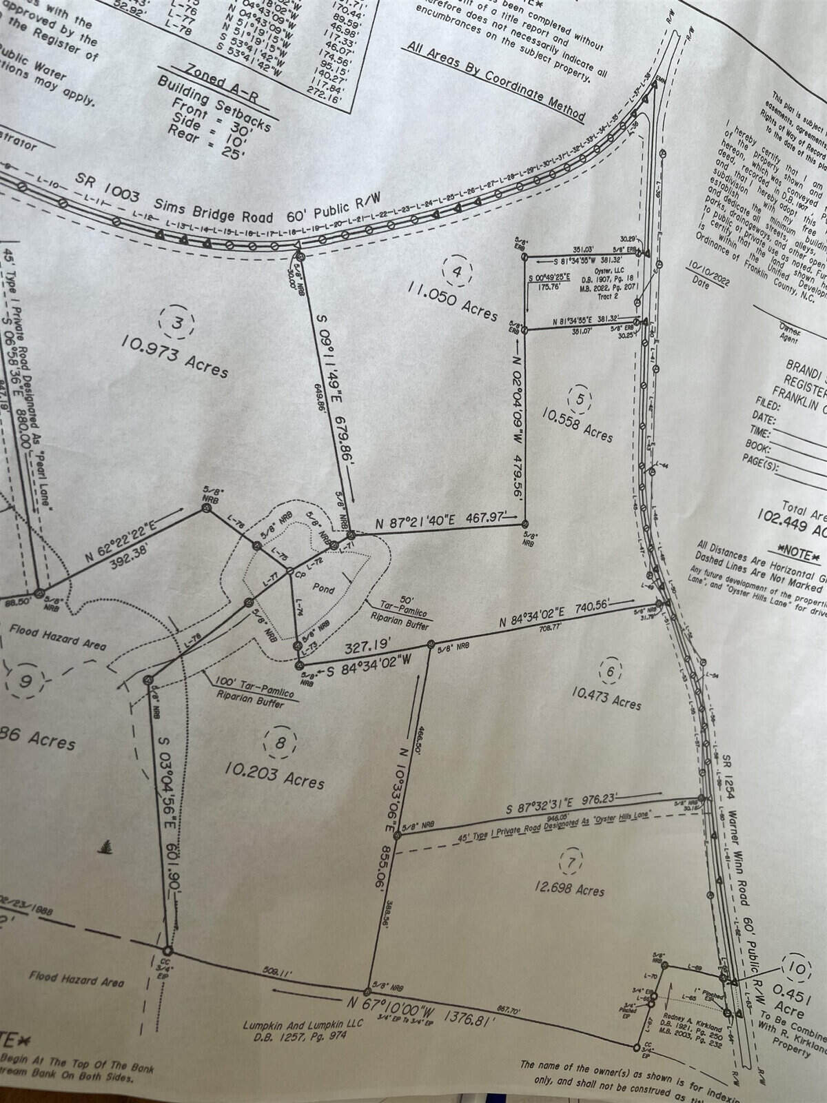 A detailed survey map displaying multiple land plots with acreages labeled. It includes various measurements, boundary lines, coordinates, road names, and lot numbers. The map appears to outline a subdivision with distinct sections for each plot of land.