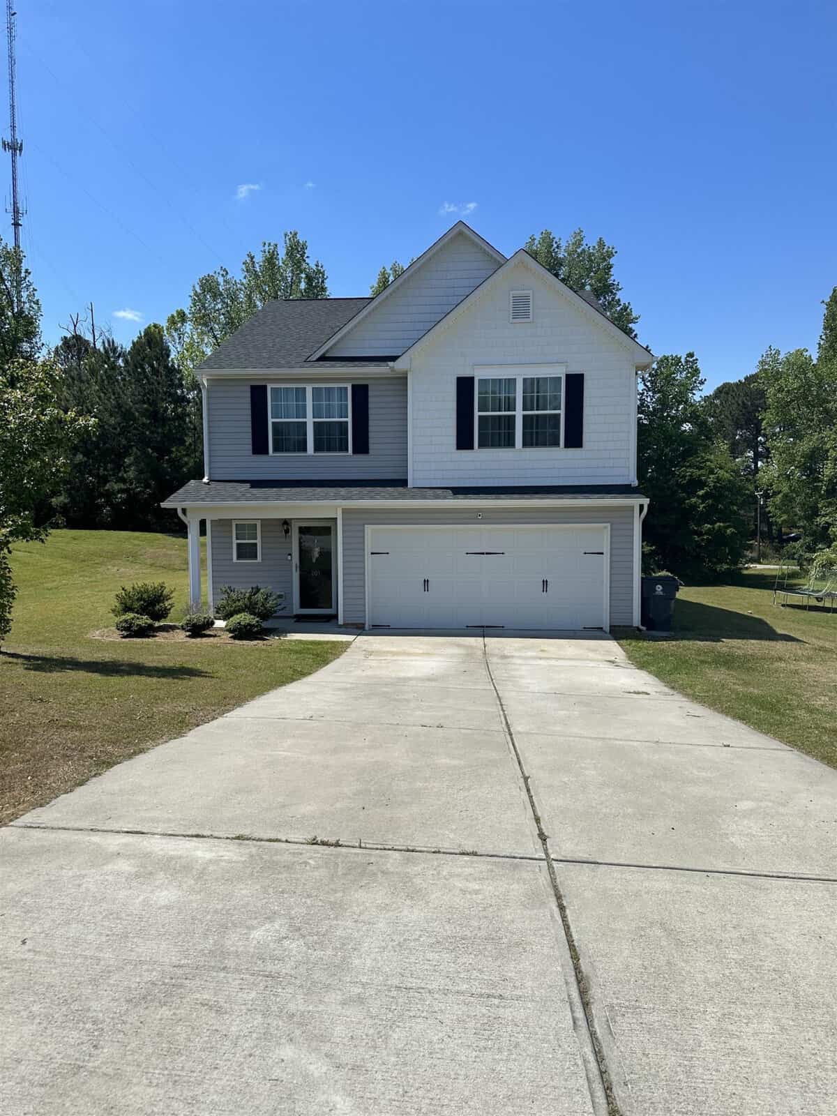 A two-story suburban home with a two-car garage and a concrete driveway on a sunny day.