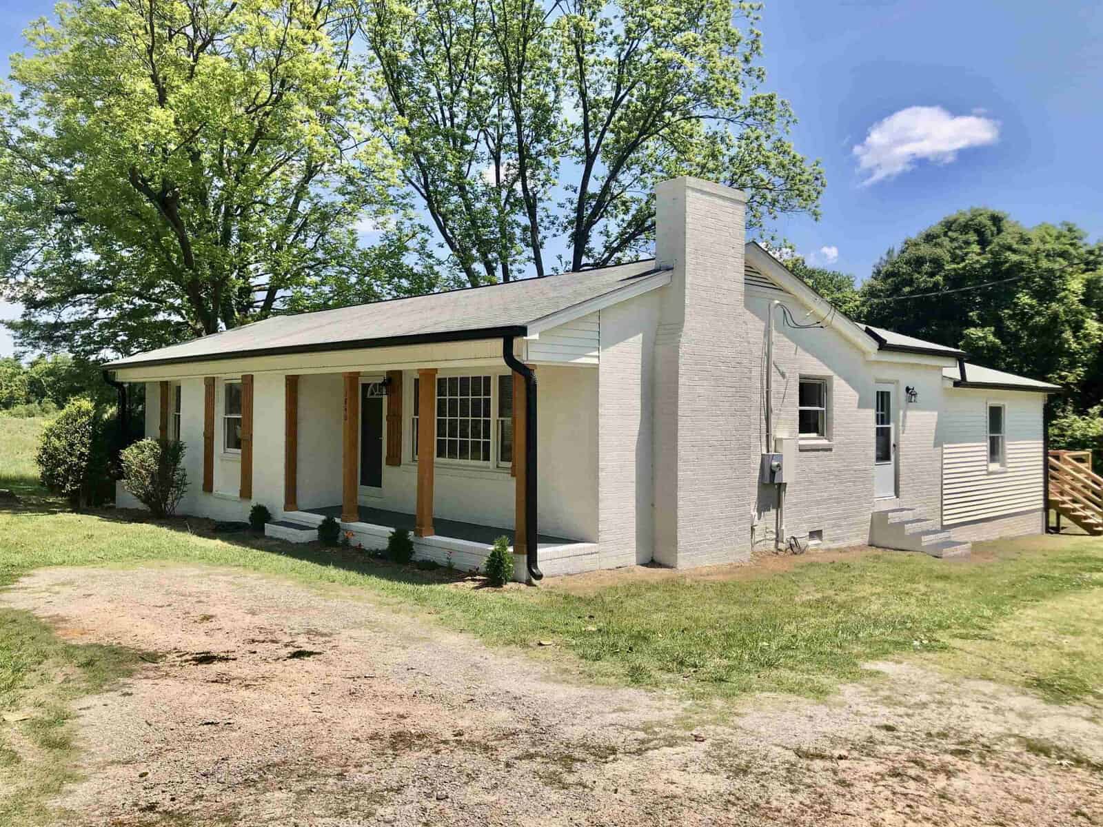 A single-story white house with a front porch and a side ramp under a clear blue sky.