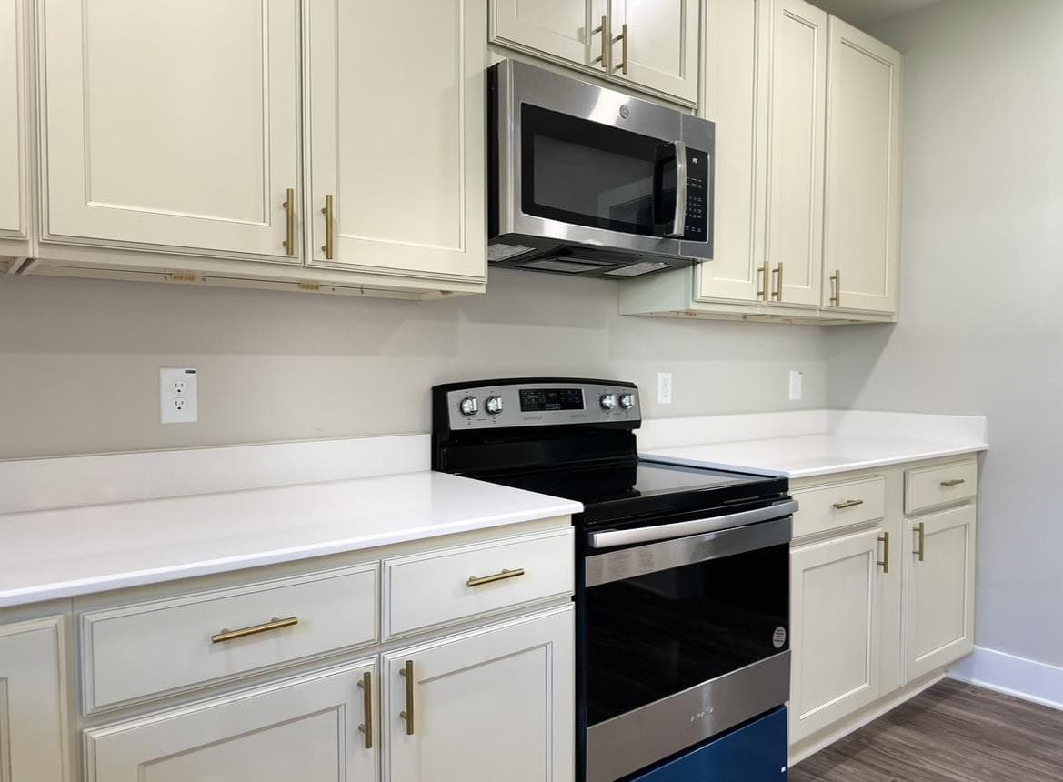 A modern kitchen with white cabinetry, stainless steel appliances, and white countertops.