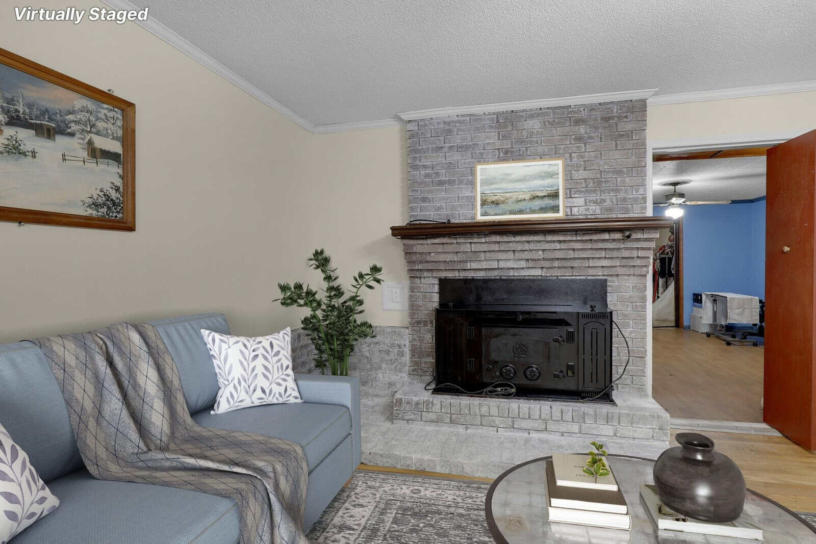 A cozily furnished living room with a gray sofa, a fireplace, and decorative elements, indicated as virtually staged.