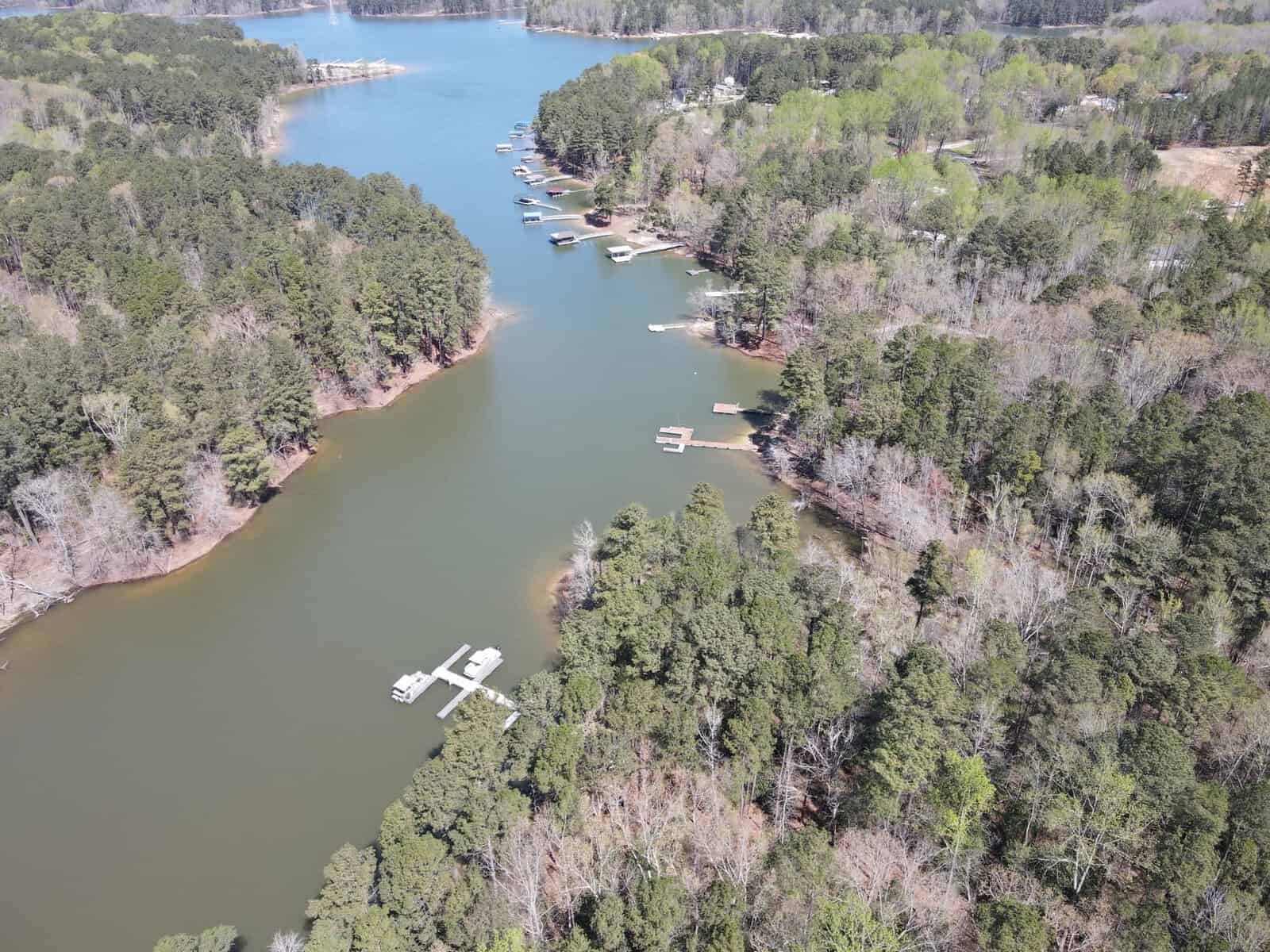 An aerial view of a serene river inlet with docks and boats at Lot 41 Spring Lane, Henderson NC, surrounded by forested land.