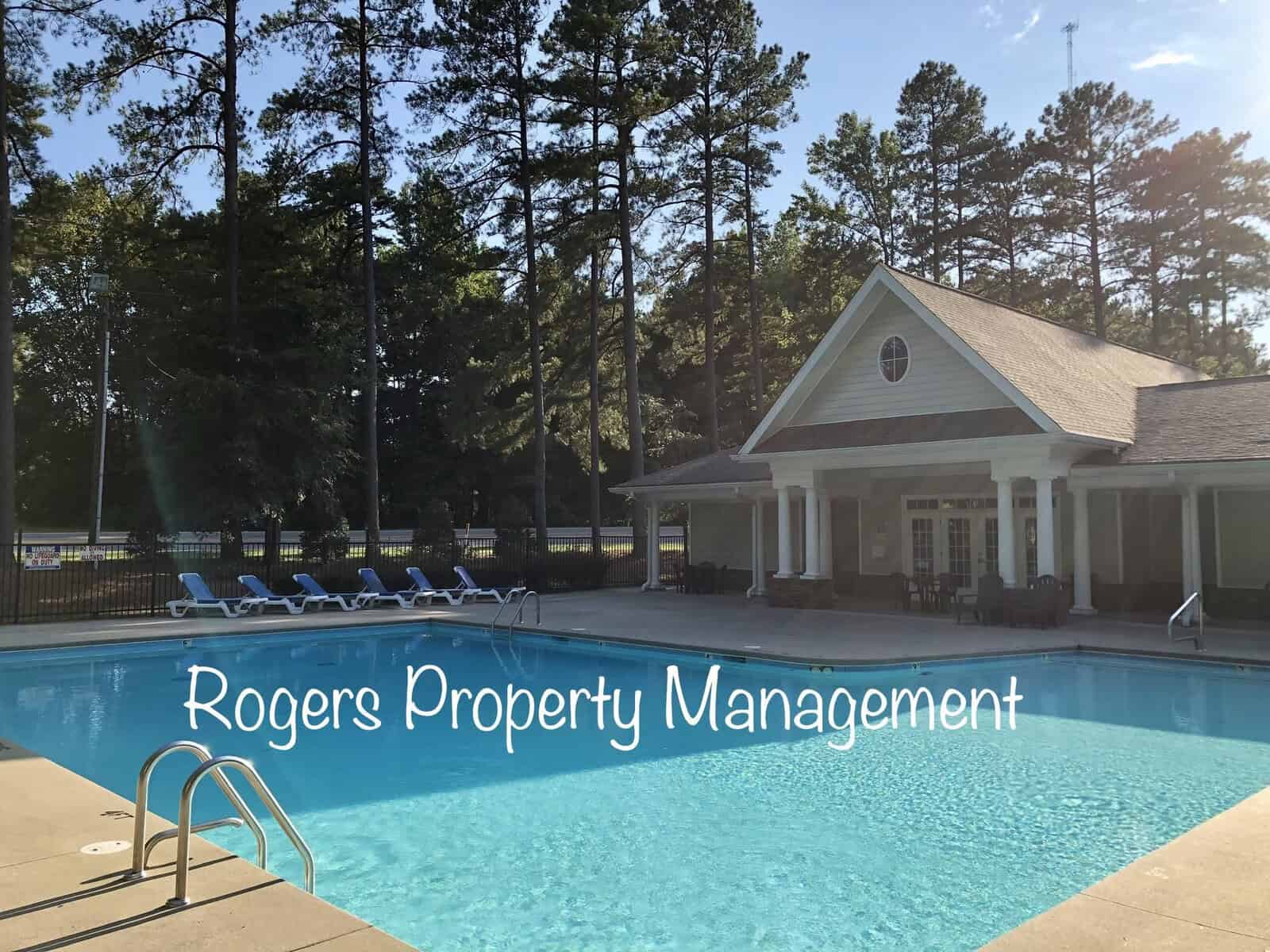 A tranquil community pool area managed by rogers property management, featuring lounge chairs and surrounded by tall pine trees in the late afternoon sunlight.