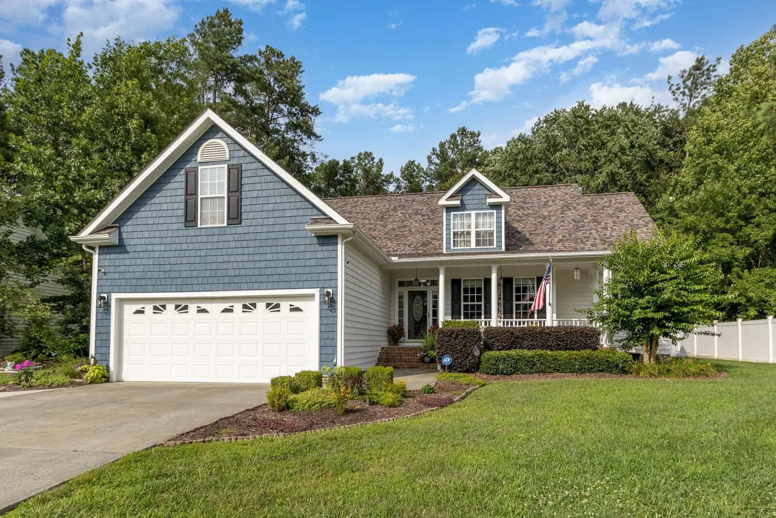 A single-family home with blue siding, a two-car garage, and a well-maintained lawn.
