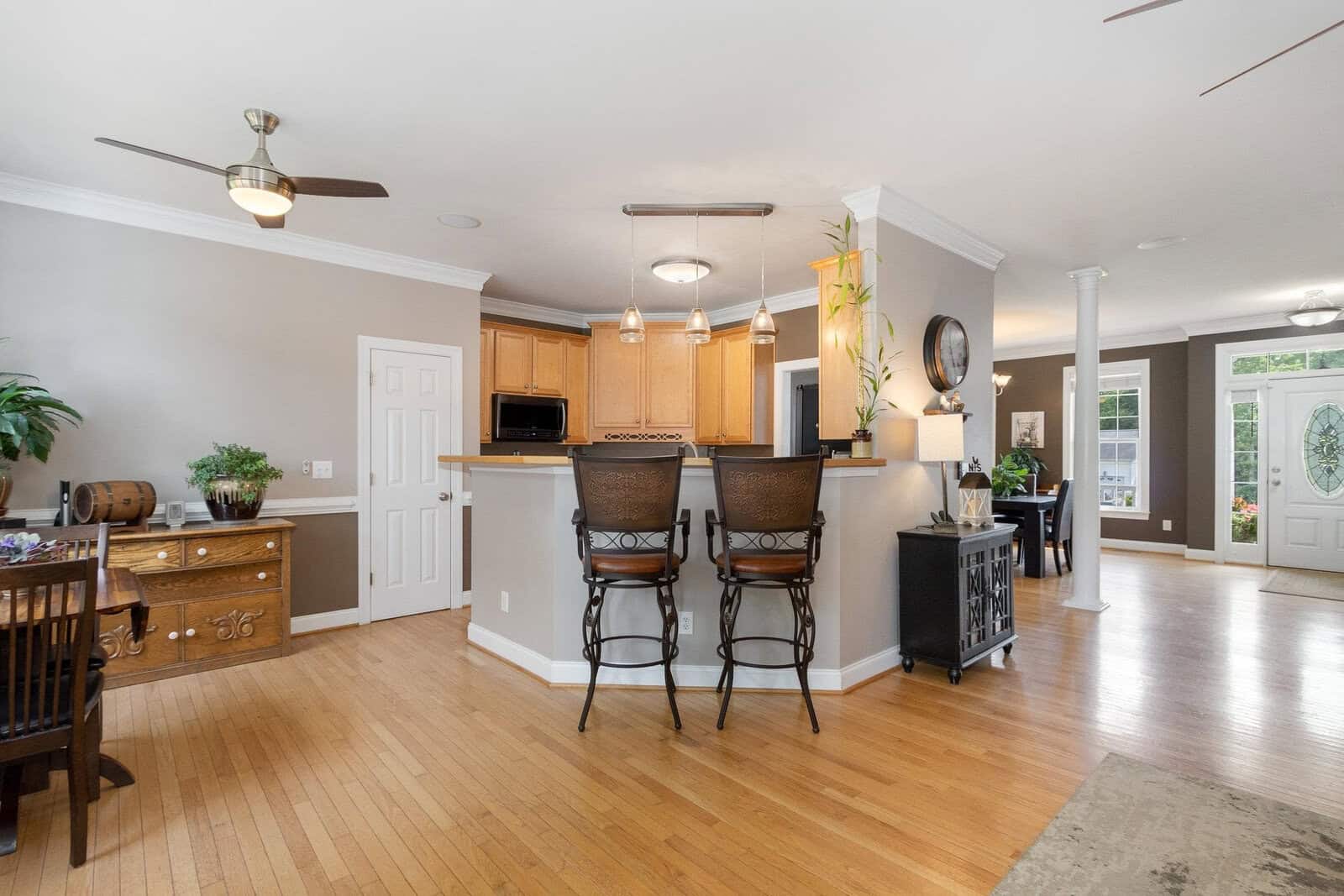 Spacious kitchen with a breakfast bar, wooden cabinets, and modern appliances, opening up to a bright dining area with hardwood floors.