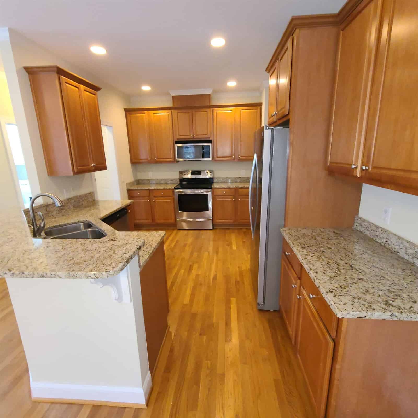 Modern kitchen with wooden cabinets, stainless steel appliances, and granite countertops.