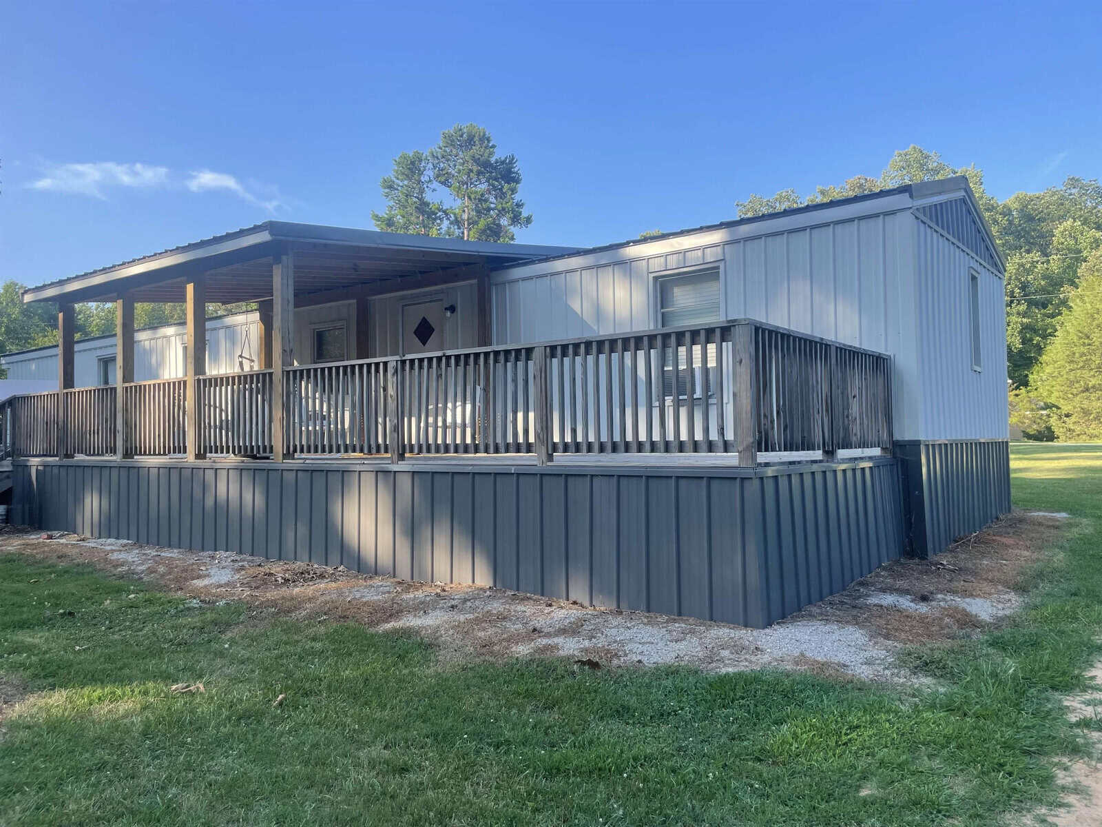 A single-story modular home with an attached front porch and railing. The structure has a sloped roof, is supported by a pier foundation, and is surrounded by a grassy lawn at 519 Waters