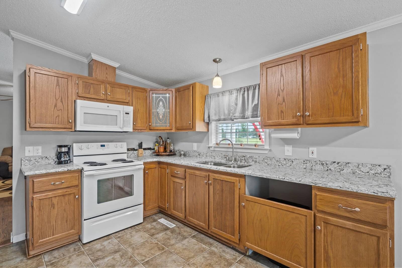 A well-lit, modern kitchen featuring wooden cabinets, granite countertops, and stainless steel appliances.