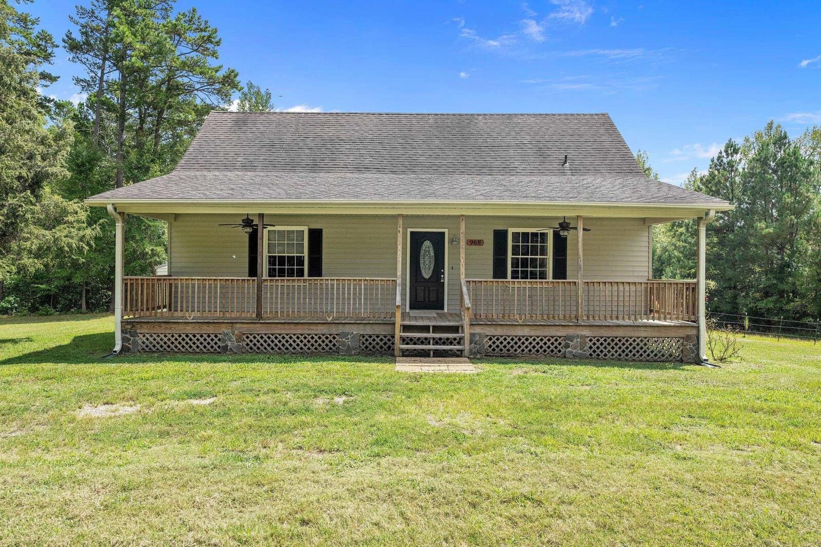A single-story house at 968 Old Hester Road, Henderson NC, boasts a symmetrical facade, featuring a centered front door flanked by two windows and a covered front porch with railing. The