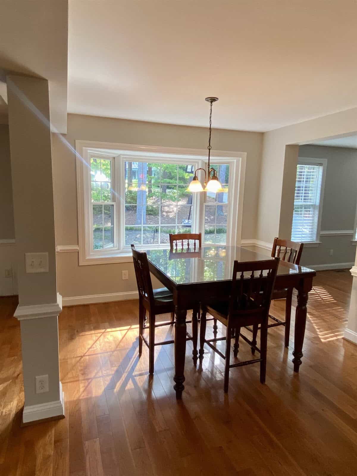 A well-lit dining room featuring a wooden table and chairs, with large windows allowing plenty of natural light to illuminate the space.