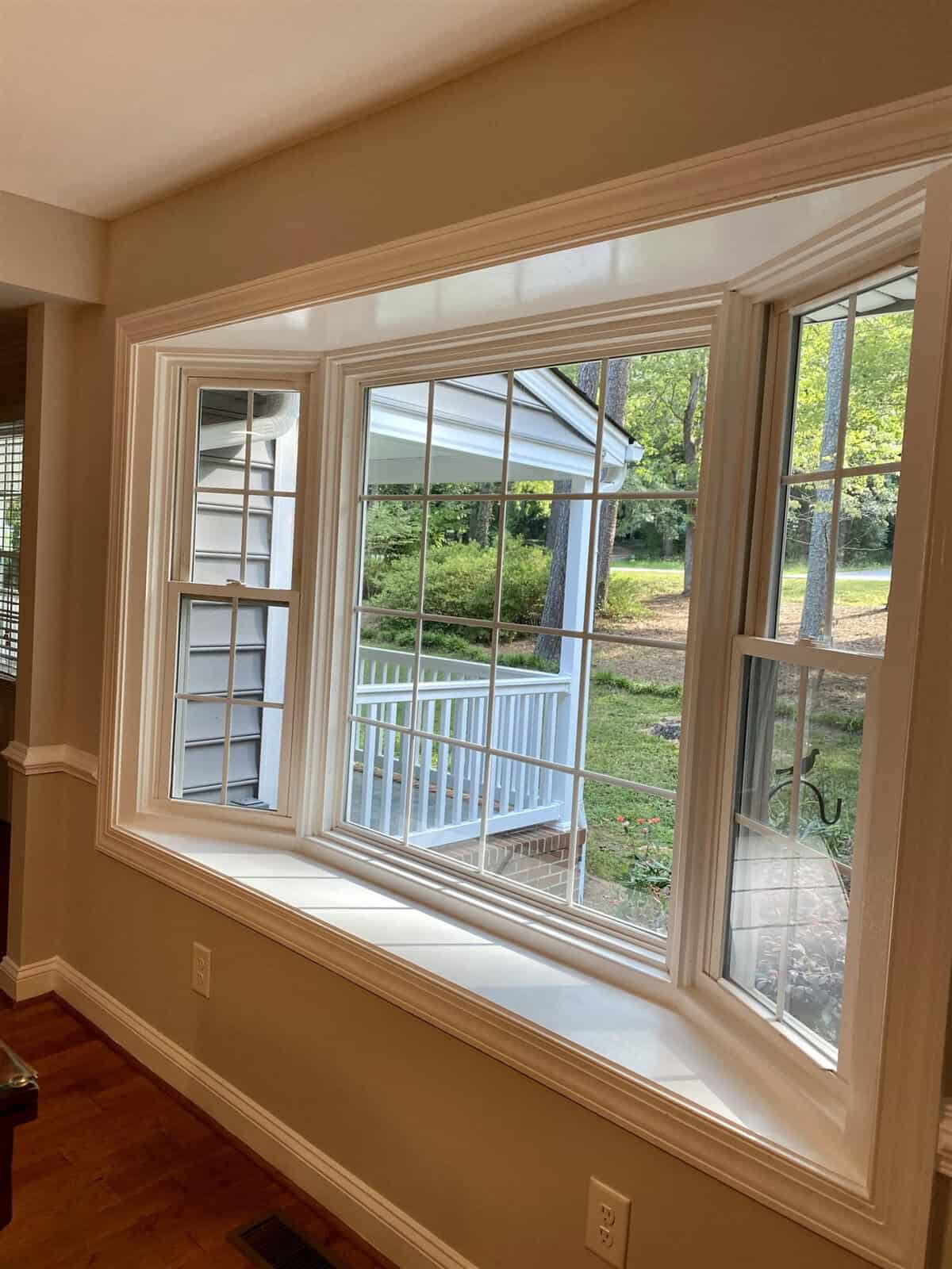 A bay window in a residential home offering a view of an outdoor deck and yard, with natural light illuminating the interior space.