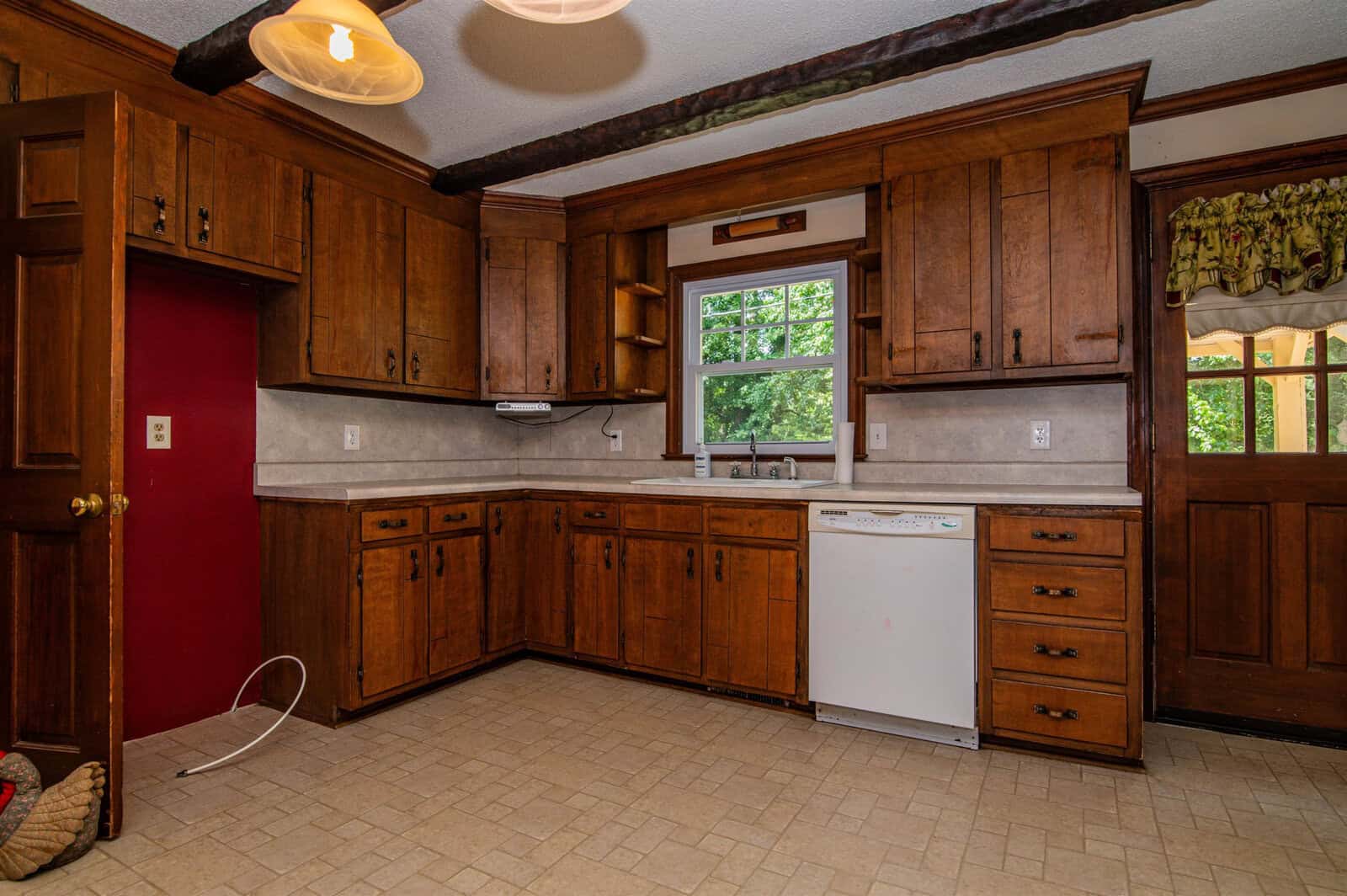 A traditional kitchen with wooden cabinetry, white countertops, a white refrigerator, and tile flooring.